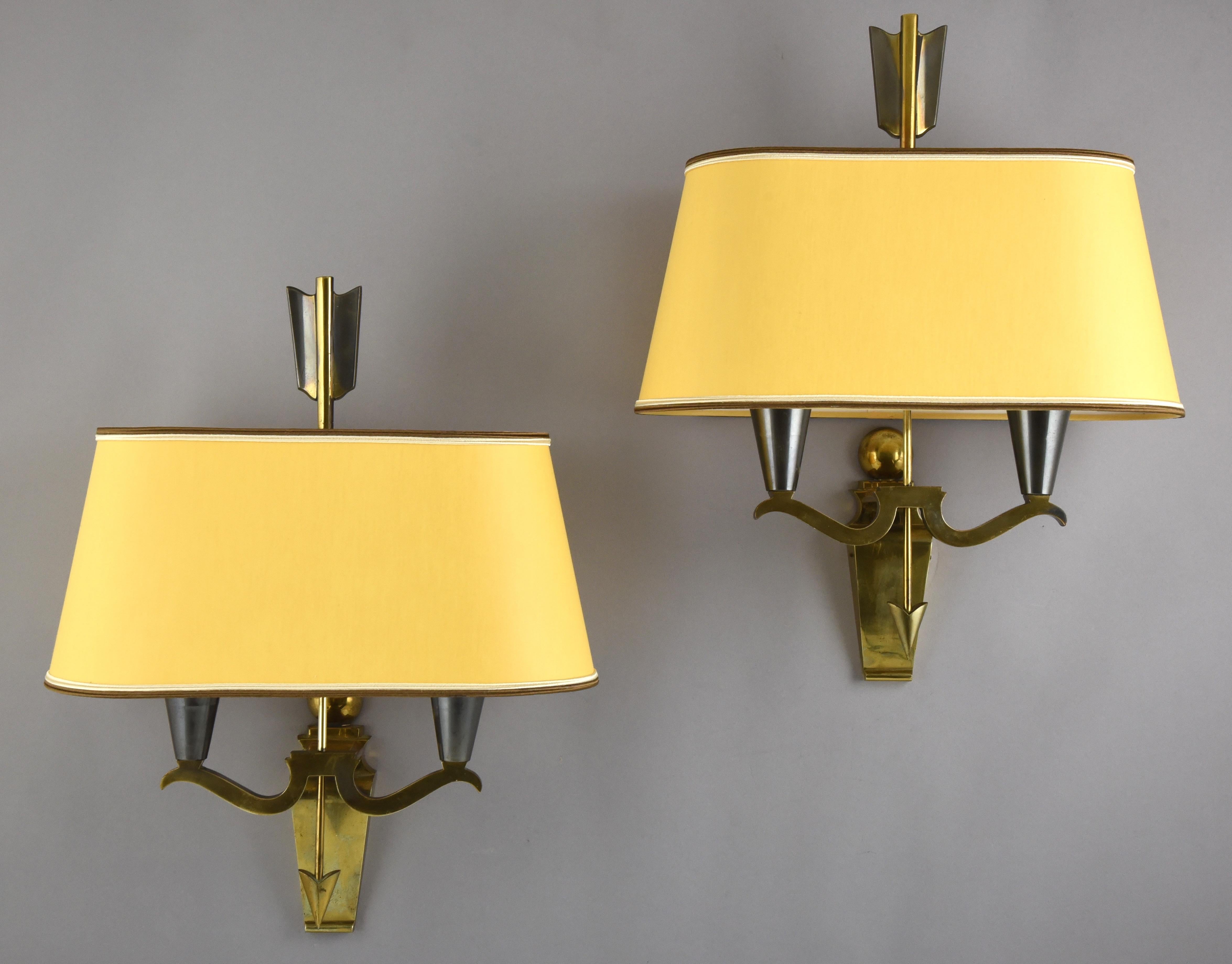 Stylish pair of midcentury arrow wall lights or sconces.
Patinated bronze frame with arrow, warm yellow fabric shades.
In the style of Maison Jansen, France circa 1960.