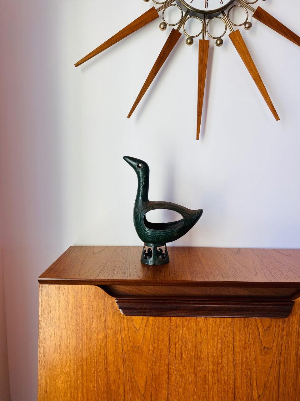 Serene, elegant, and handsome bronze sculpture. Simple lines that are undeniably midcentury. Finely hand casted (evokes Brutalist), it boasts a handsome verdigris patina. This avian figure is casted with great detail while posed on a pedestal of the