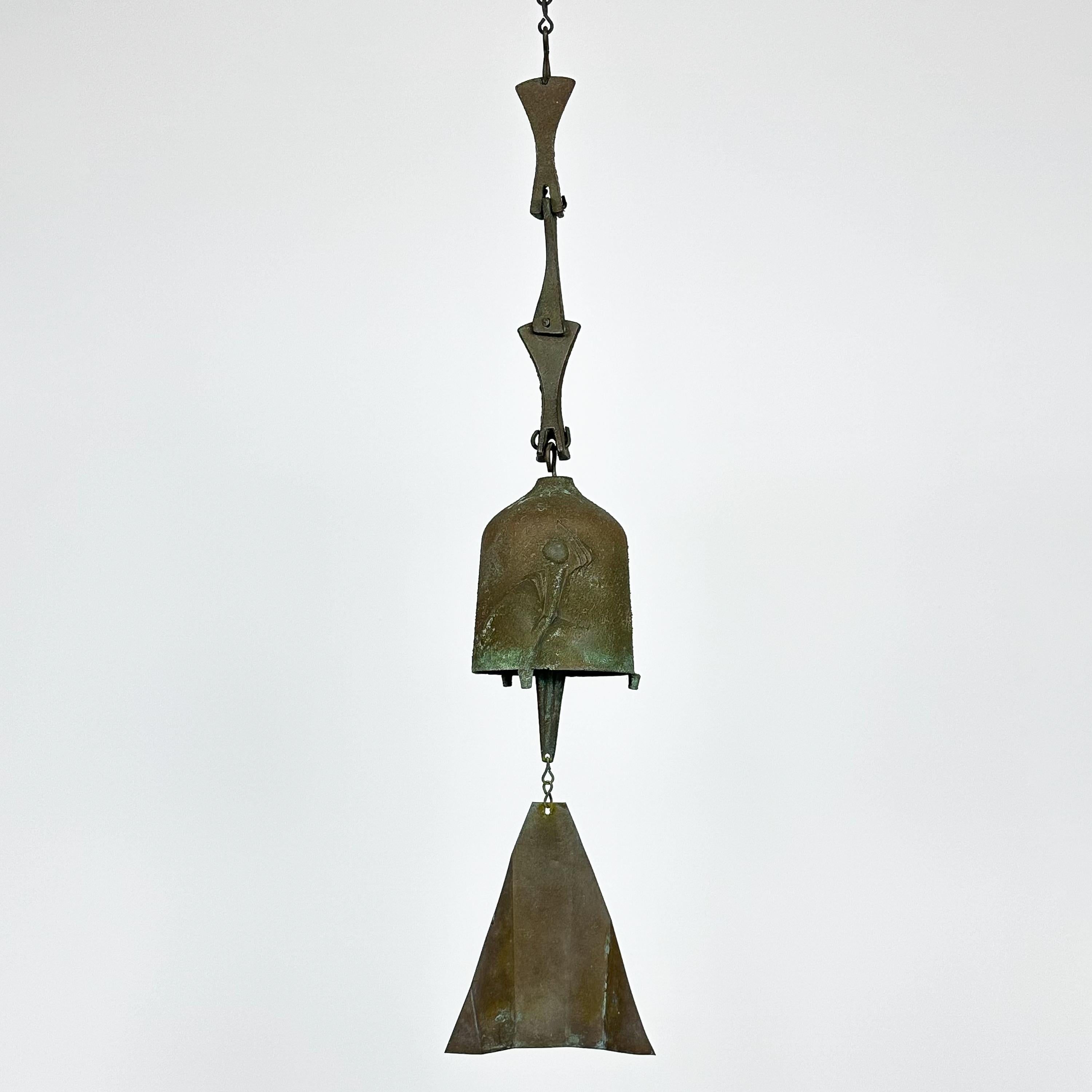 A vintage Brutalist bronze bell / wind chime designed by architect, Paolo Soleri for Arcosanti , circa 1970s. This gorgeous cast solid bronze Soleri bell features a beautiful patina, abstract design on the bell and three part hinged bronze chain.