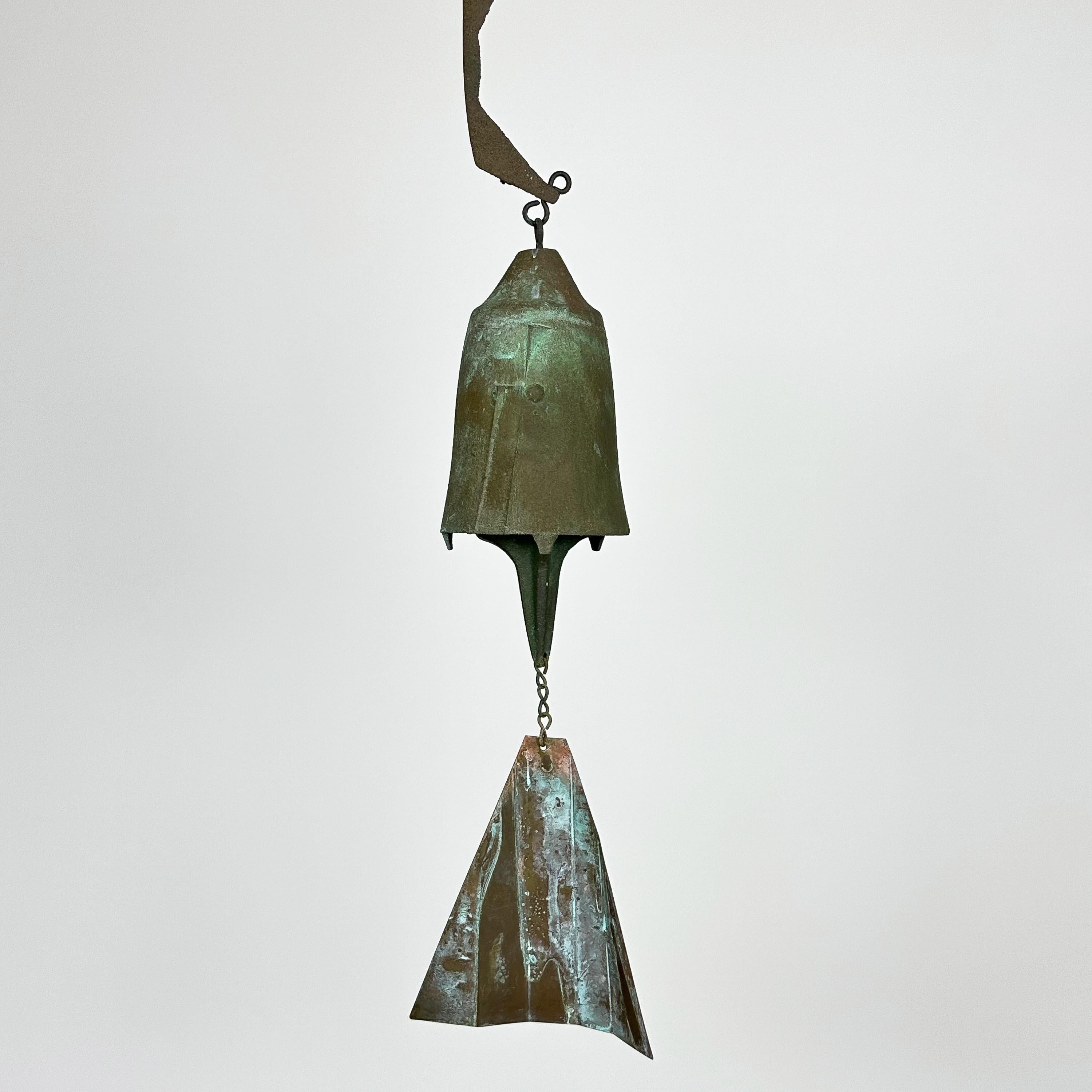 A vintage Brutalist bronze bell / wind chime designed by architect, Paolo Soleri for Arcosanti , circa 1970s. This gorgeous cast solid bronze Soleri bell features a beautiful patina, abstract design on the bell and two-part S shaped hinged bronze