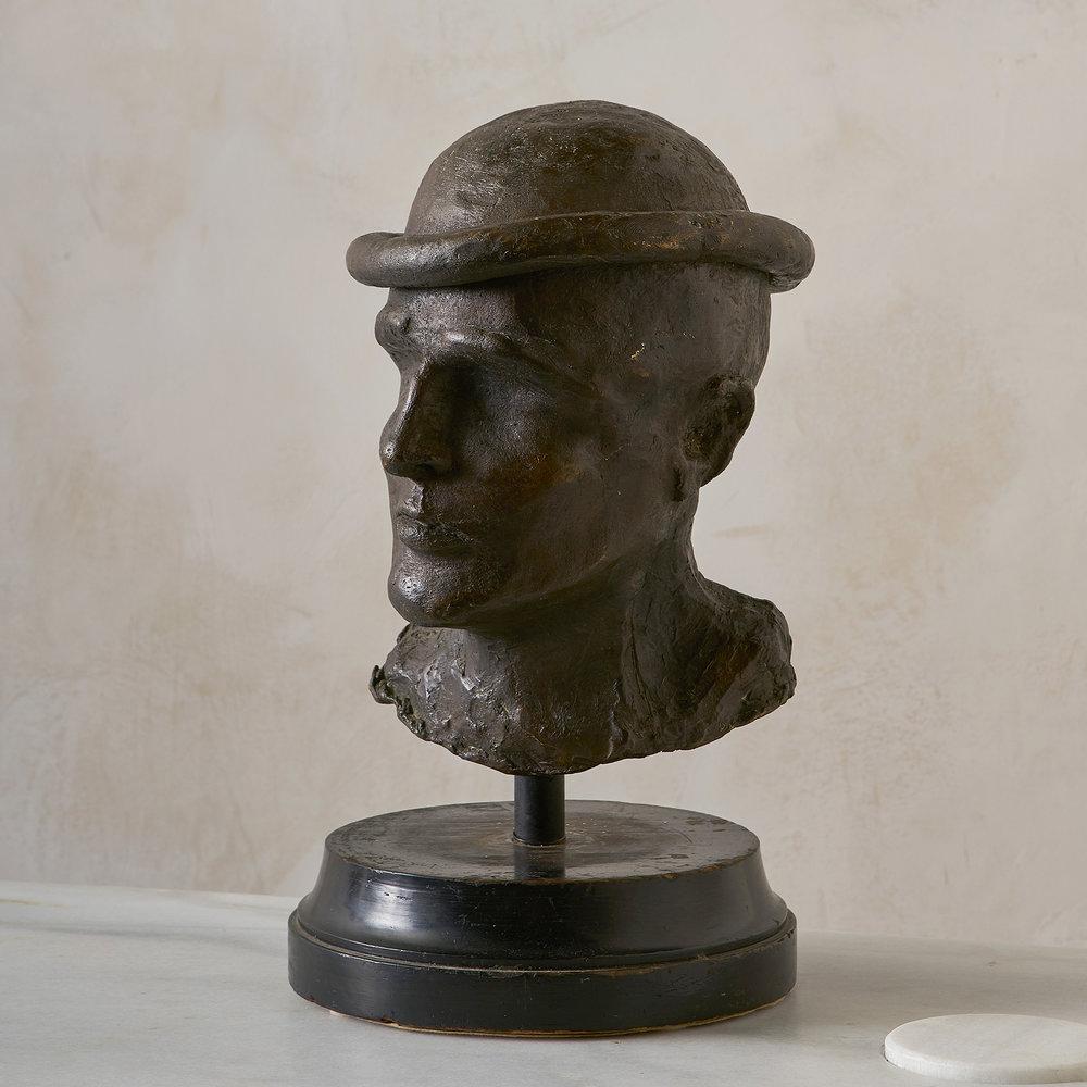 A cast bronze bust of a male figure that is signed by the artist and stamped “ROME 1969”. Signature appears to read “Bruce Walke”.