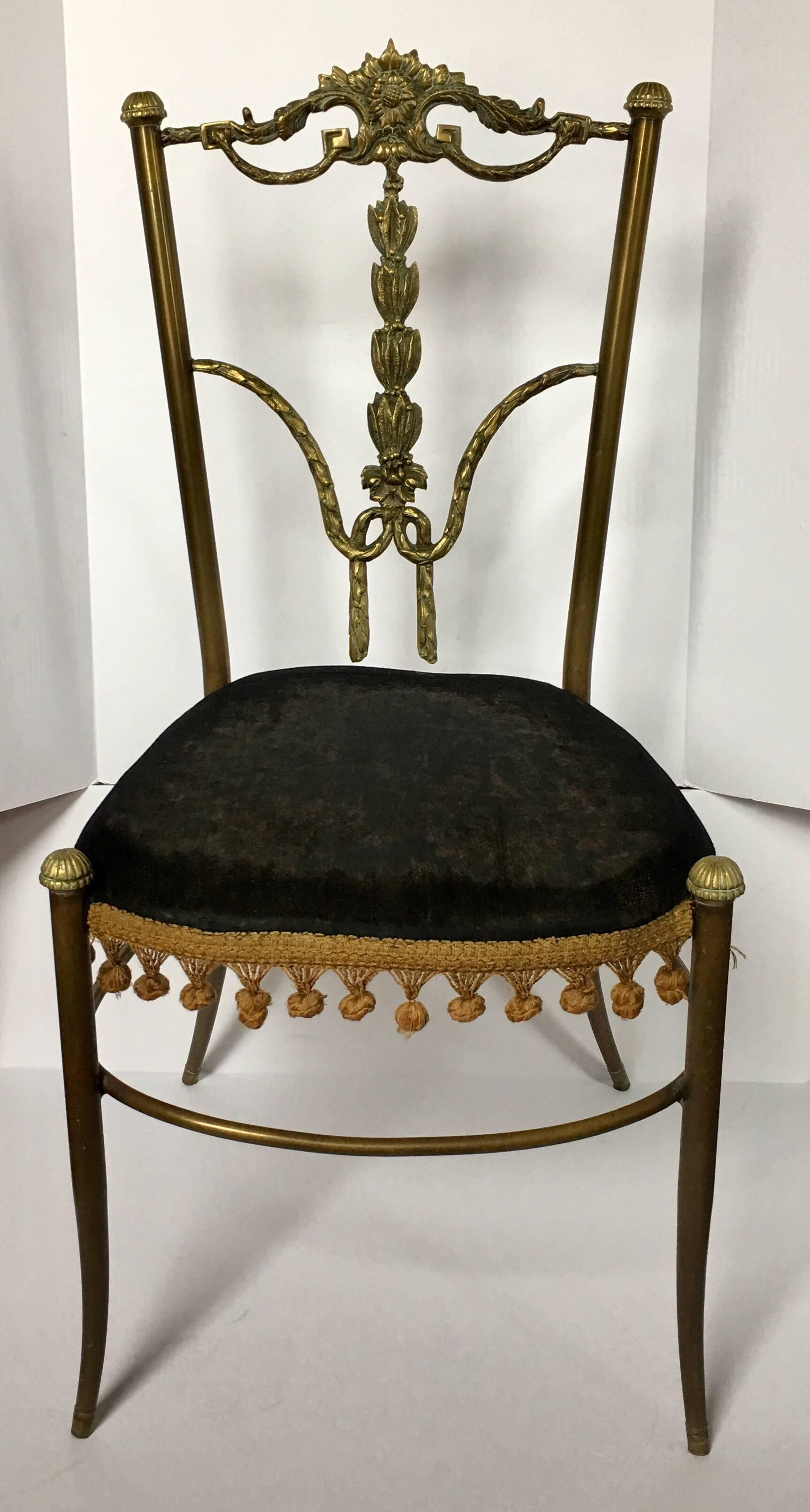 Chaise de bureau ou d'appoint en métal bronze des années 1950, dont le dossier est orné de motifs de guirlandes florales drapées et de détails en forme de clé grecque. Le siège est en velours noir d'origine avec des franges dorées.
