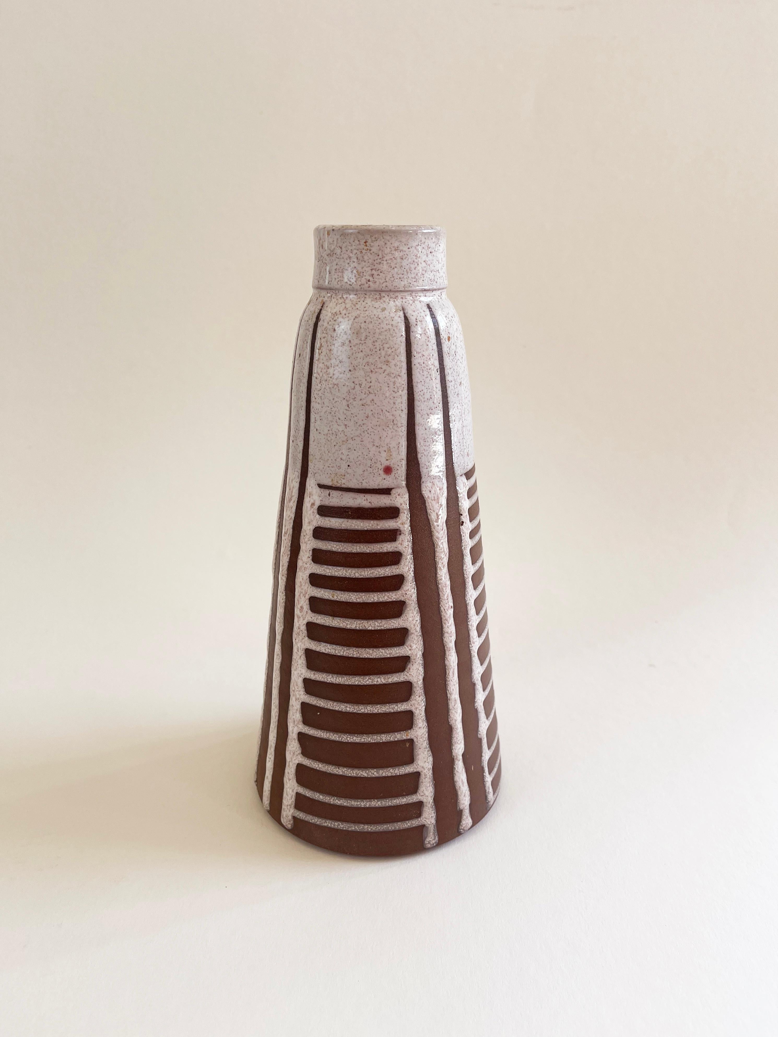 Expressive Scandinavian style Mid Century Modern handmade ceramic vase with an enthnical abstract pattern.
Fat Lava ceramic in beige with tiny dots on a ''spared'' dark coffee brown base material.
The glaze at the inner rim comes in a mottled
