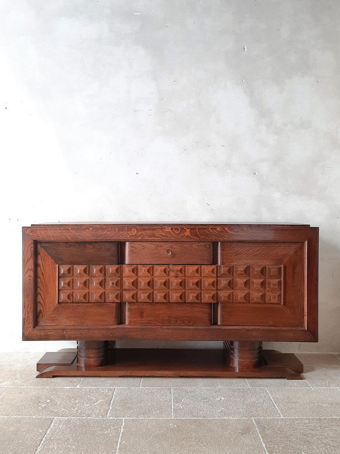 Midcentury brown oak sideboard by Charles Dudouyt, 1940s. Beautiful sideboard in pre-Brutalist Art Deco style decorated with typical geometric shapes of Dudouyt. The base gives this sideboard an extra sturdy character.

Dimensions: H 102 x W 200 x