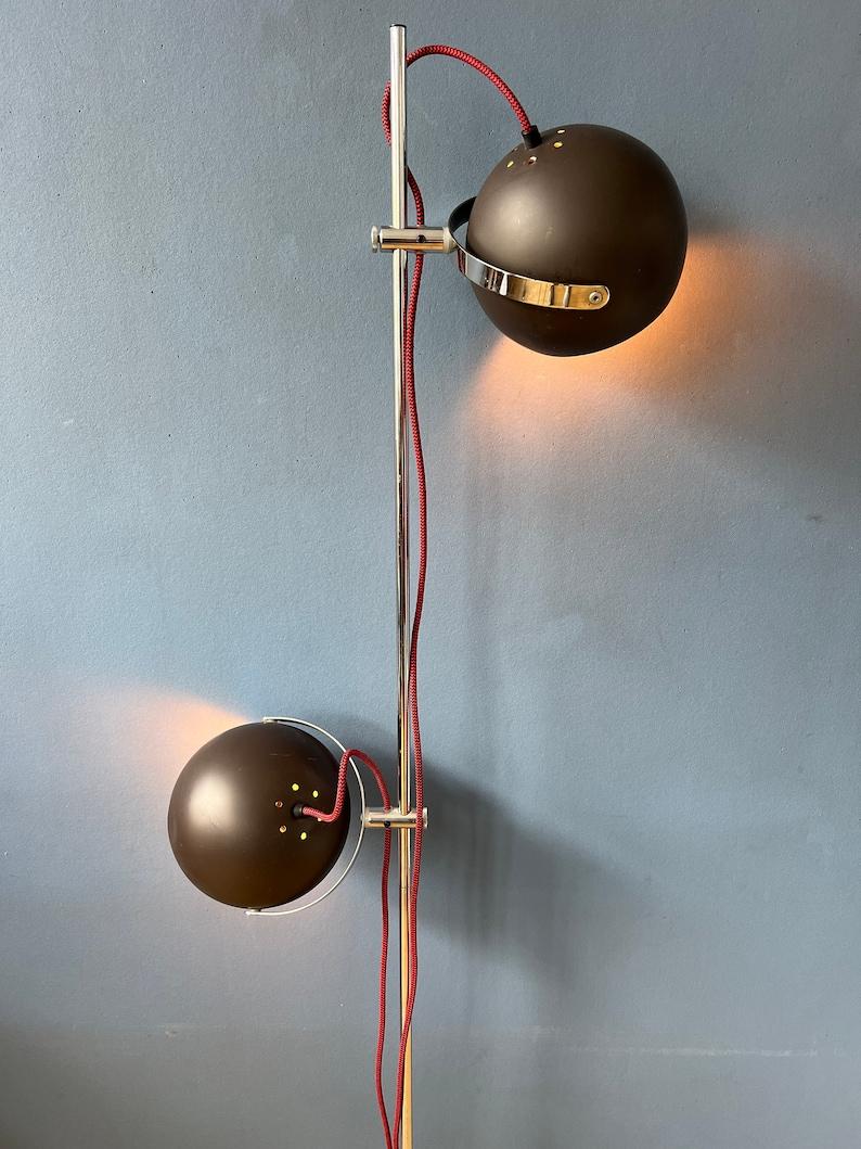 Mid century space age eyeball floor lamp in mat brown colour. The metal shades can be turned in any way desirable and move up and down the base. The lights can switched on separately or simultaneously. The lamp requires two E27/26 lightbulbs and