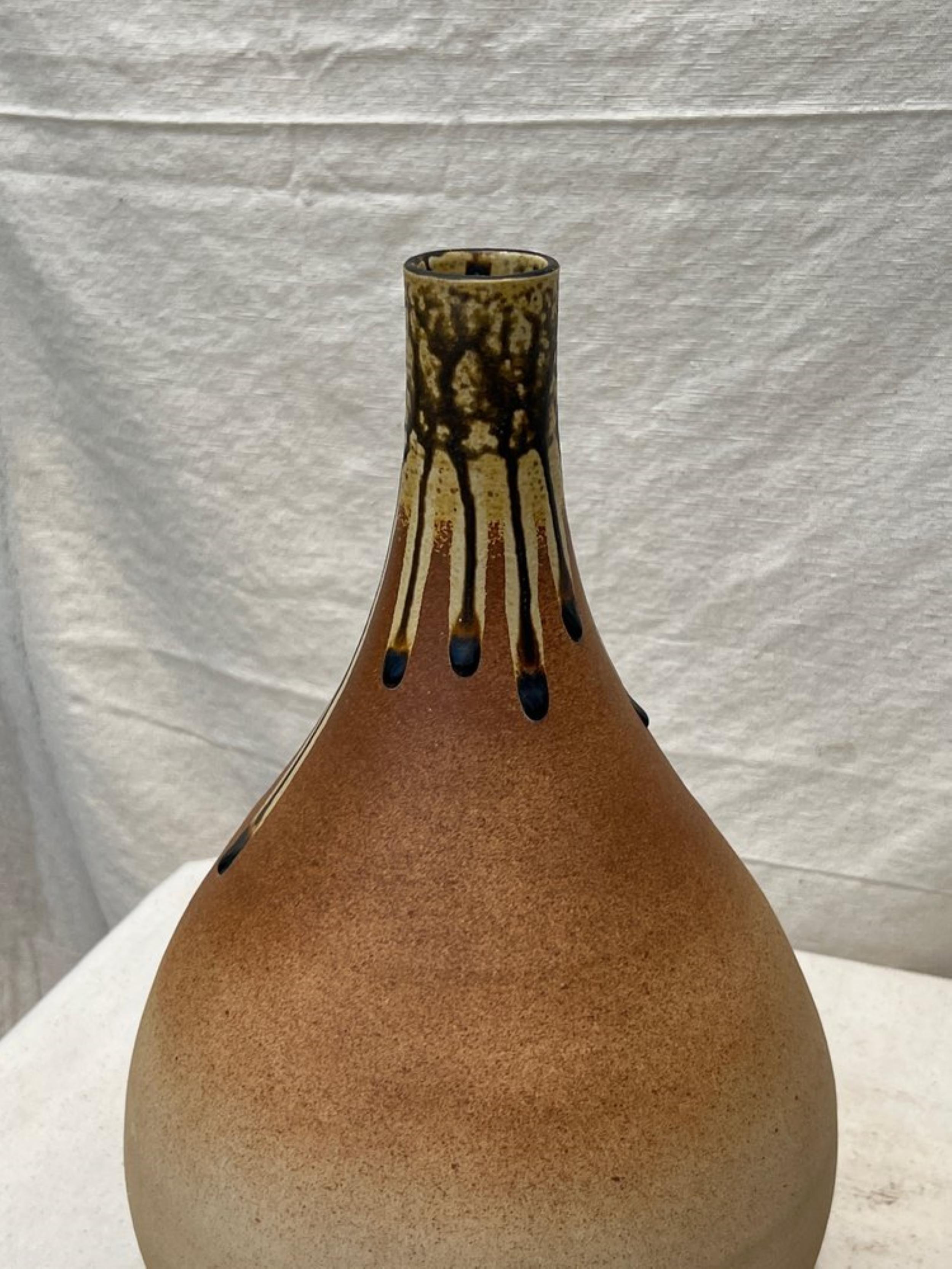 Die Mitte des 20. Jahrhunderts in Handarbeit gefertigte braune Tropfenvase aus Keramik zeichnet sich durch eine unverwechselbare Tropfglasur aus. Dieses elegante Stück verkörpert den Stil und die Raffinesse dieser Zeit.

Abmessungen: 9,5