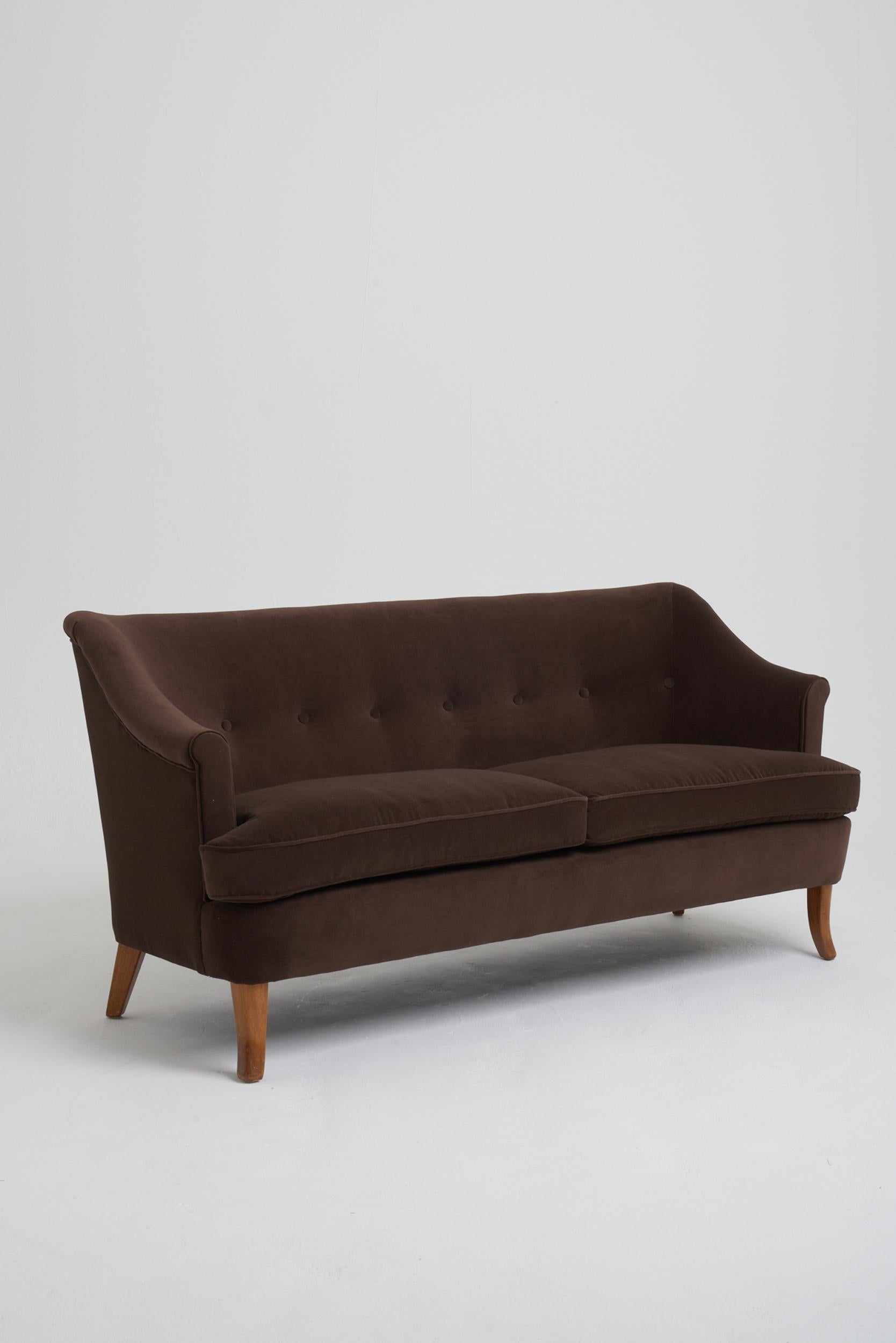 A mid-century chocolate brown velvet buttoned sofa.
Sweden, Circa 1950.