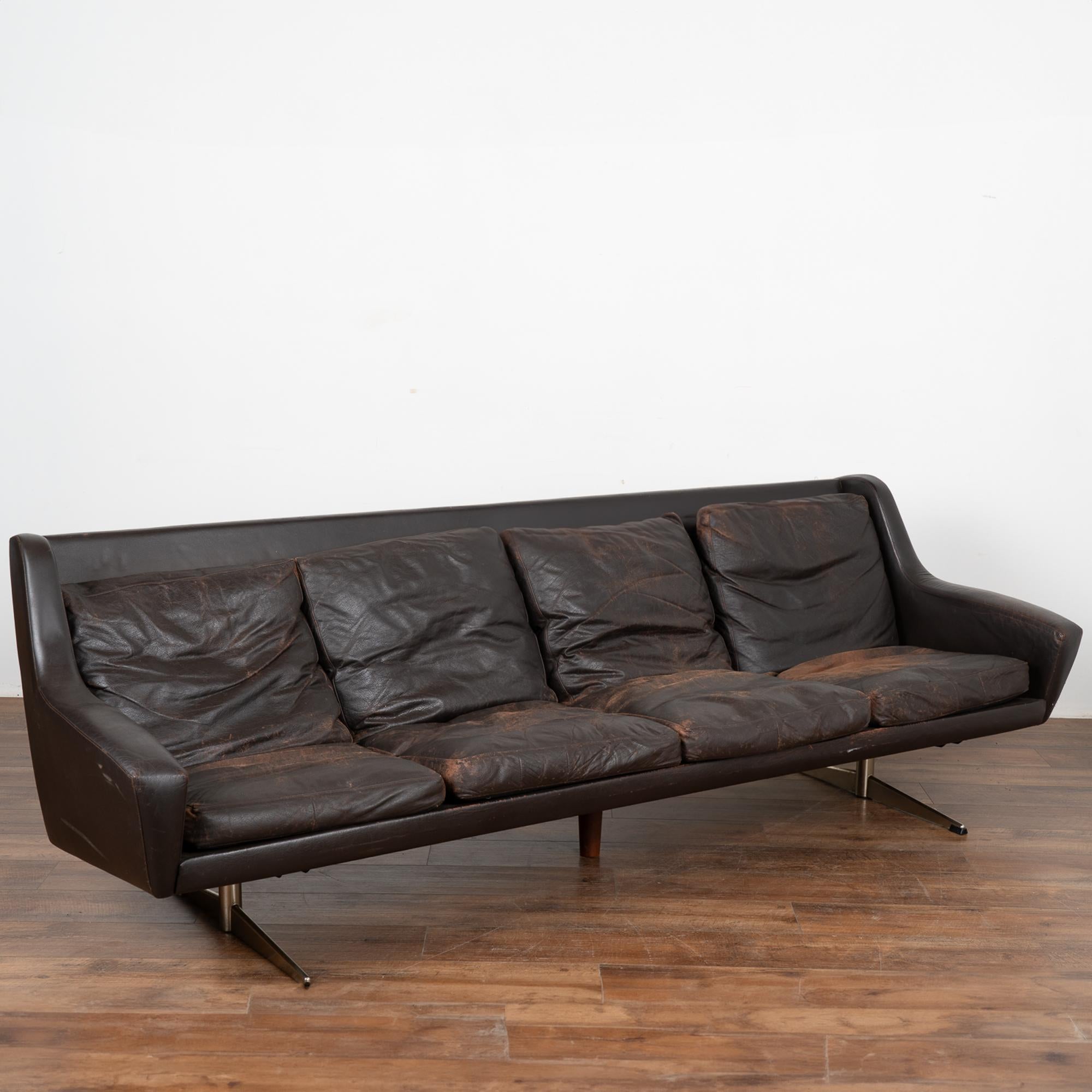 Mid-century modern brown leather four-seat sofa with removable cushions and chrome feet.
The years of use are revealed in the aged patina of the leather, including impressions, scuffs/scratches, discoloration, abrasions, sagging, etc.  which all add