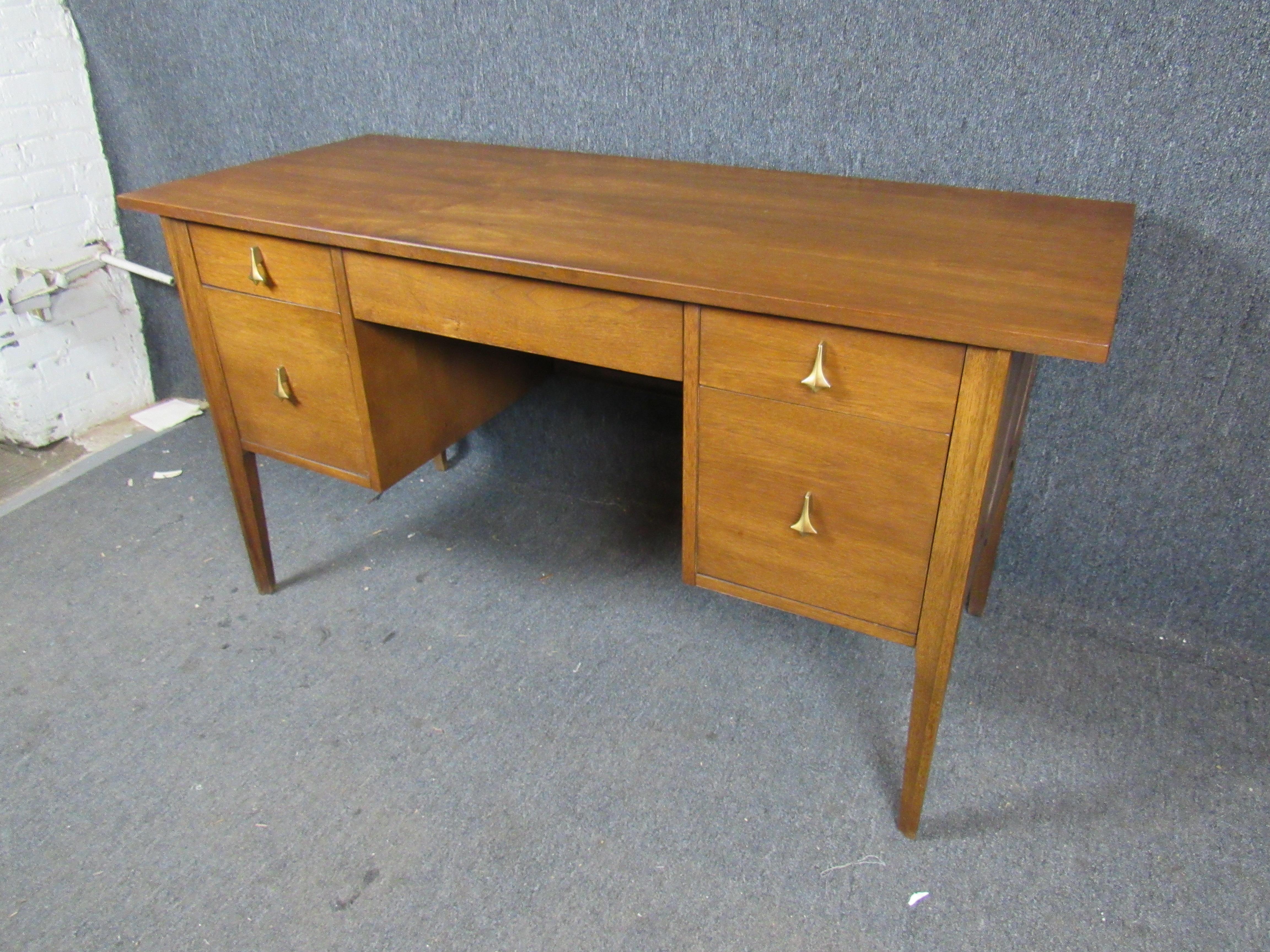 Here is a stunning and rare executive desk from Broyhill Furniture's seminal Brasilia line. Fine walnut shows off a stunning, rich wood grain while attractive brass hardware and a beautiful finished back with a cane inlay add to the vintage appeal.
