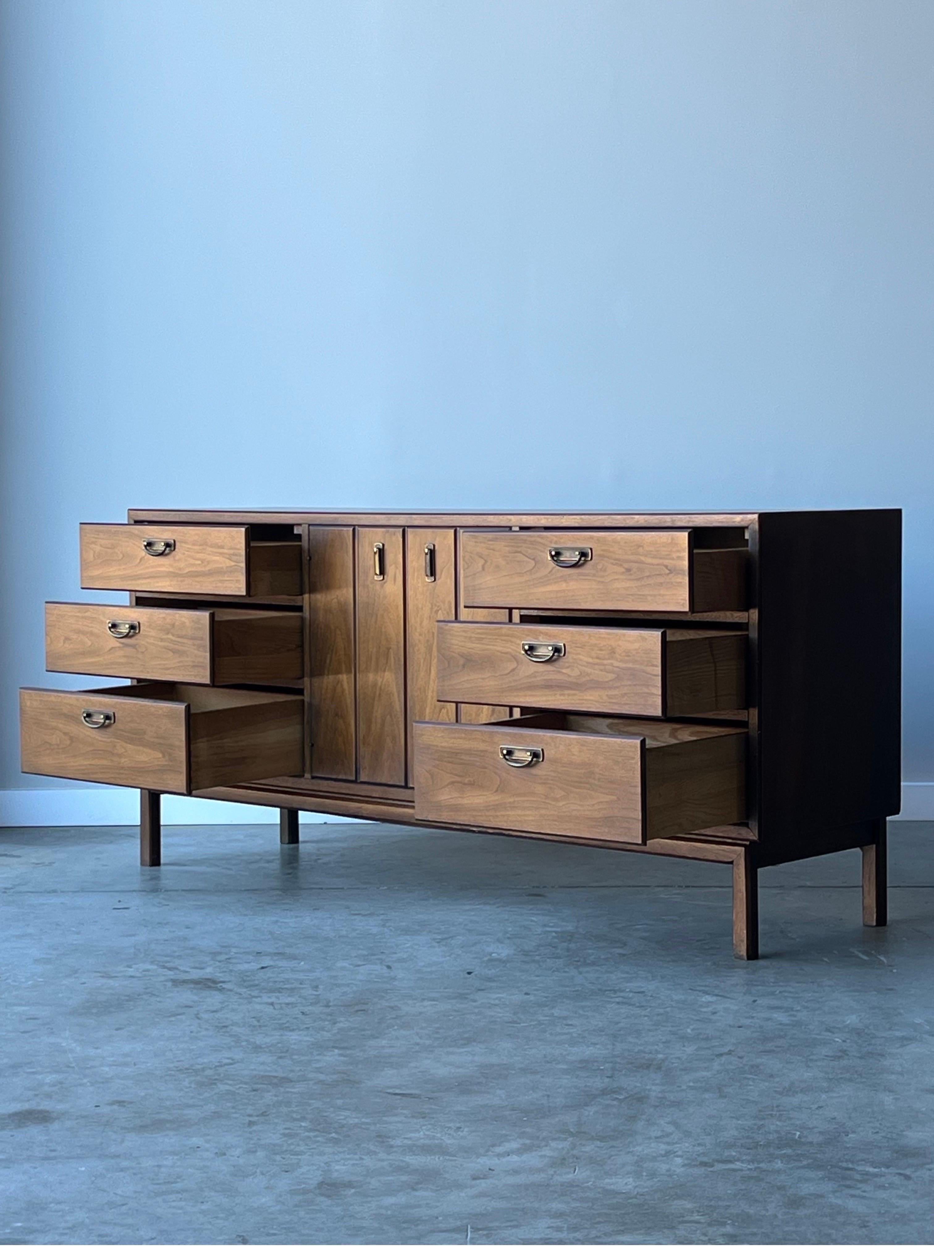 Beautiful Mid Century Broyhill Premier walnut nine drawer dresser. This item is equipped smooth action drawers and lovely brass hardware. Gorgeous details with solid stance and rich wood grain. In excellent condition with a refinished top and only