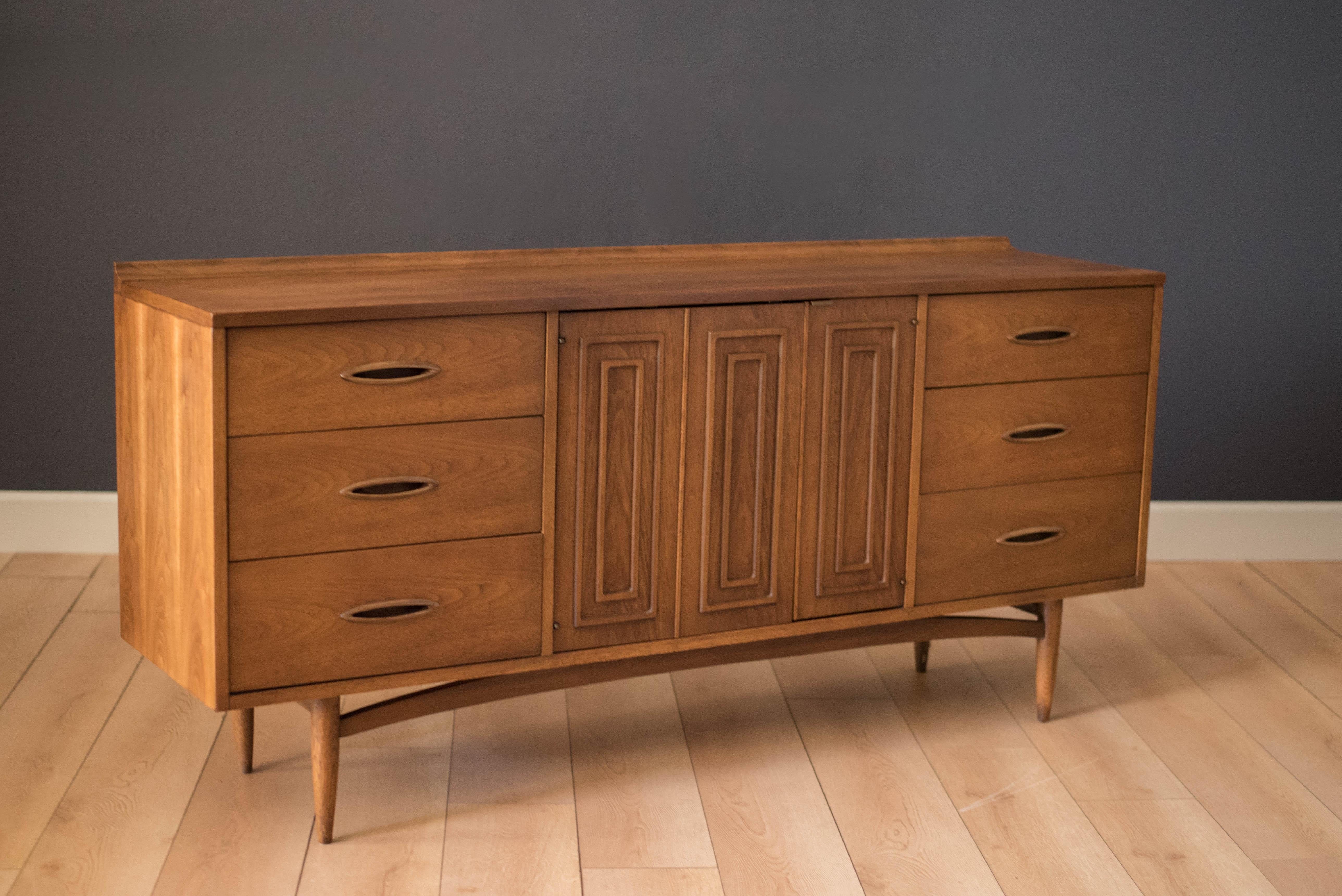 Vintage Sculptra low triple dresser manufactured by Broyhill in walnut. This piece features the line's signature cat eye pulls and sculpted raised edge in oak. Offers plenty of storage and is equipped with nine dovetailed drawers.