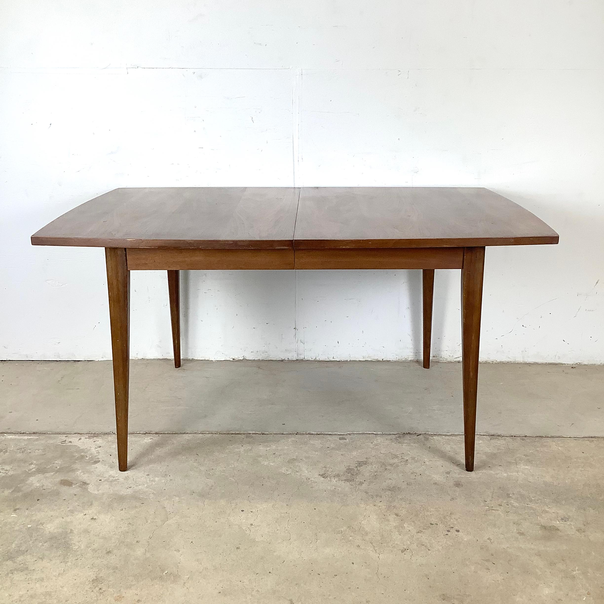 This mid-century walnut dining table, crafted in the style of Broyhill’s celebrated designs, captures the sleek elegance of American modernism in the early 1960s. A beautifully grained walnut surface, clean lines, and gently tapered legs reflect the