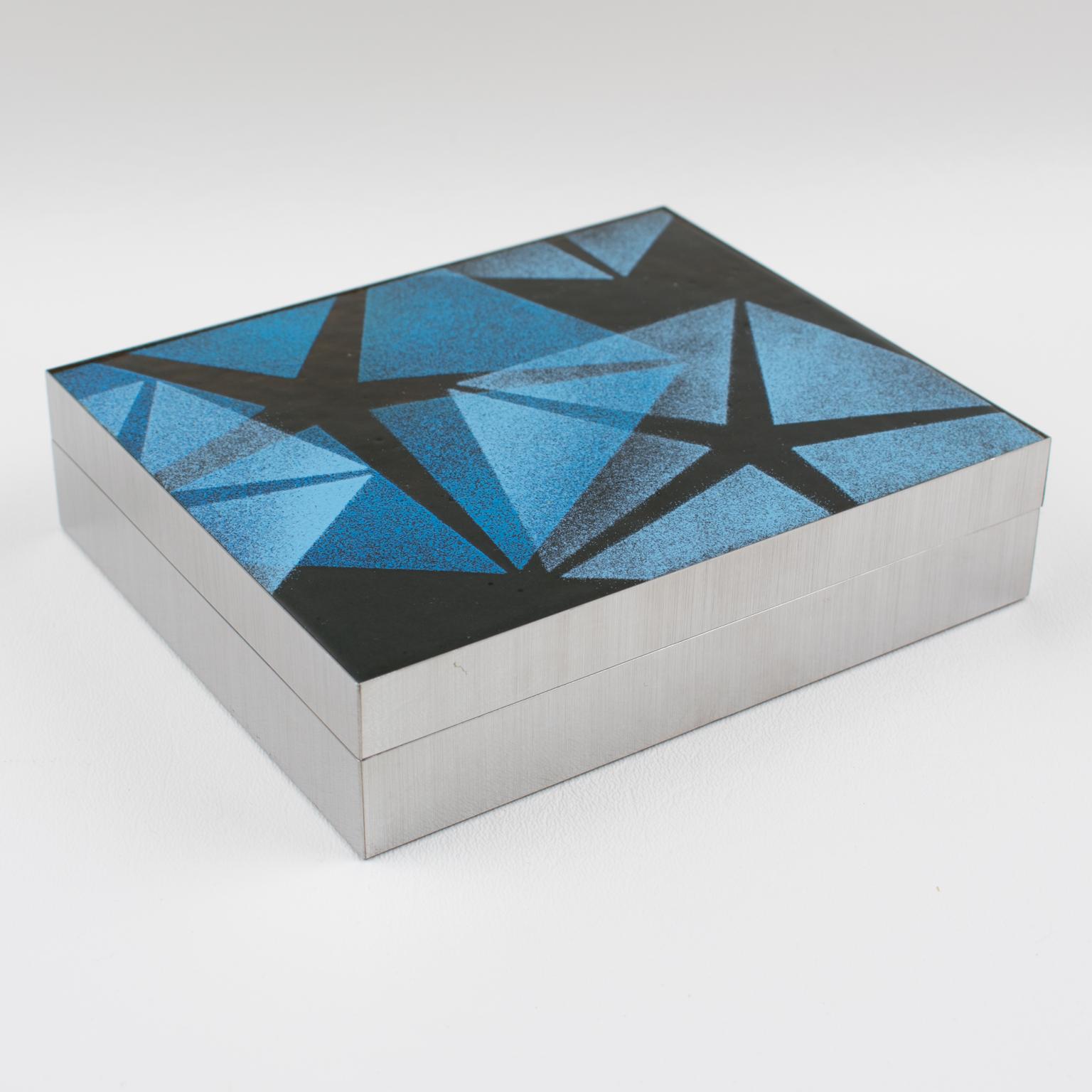 This beautiful 1970s decorative lidded box was crafted in Italy. This piece features a rectangular shape with a brushed aluminum base and enamel-on-copper lid with a geometric stylized star design. The piece boasts cobalt blue, black, and white