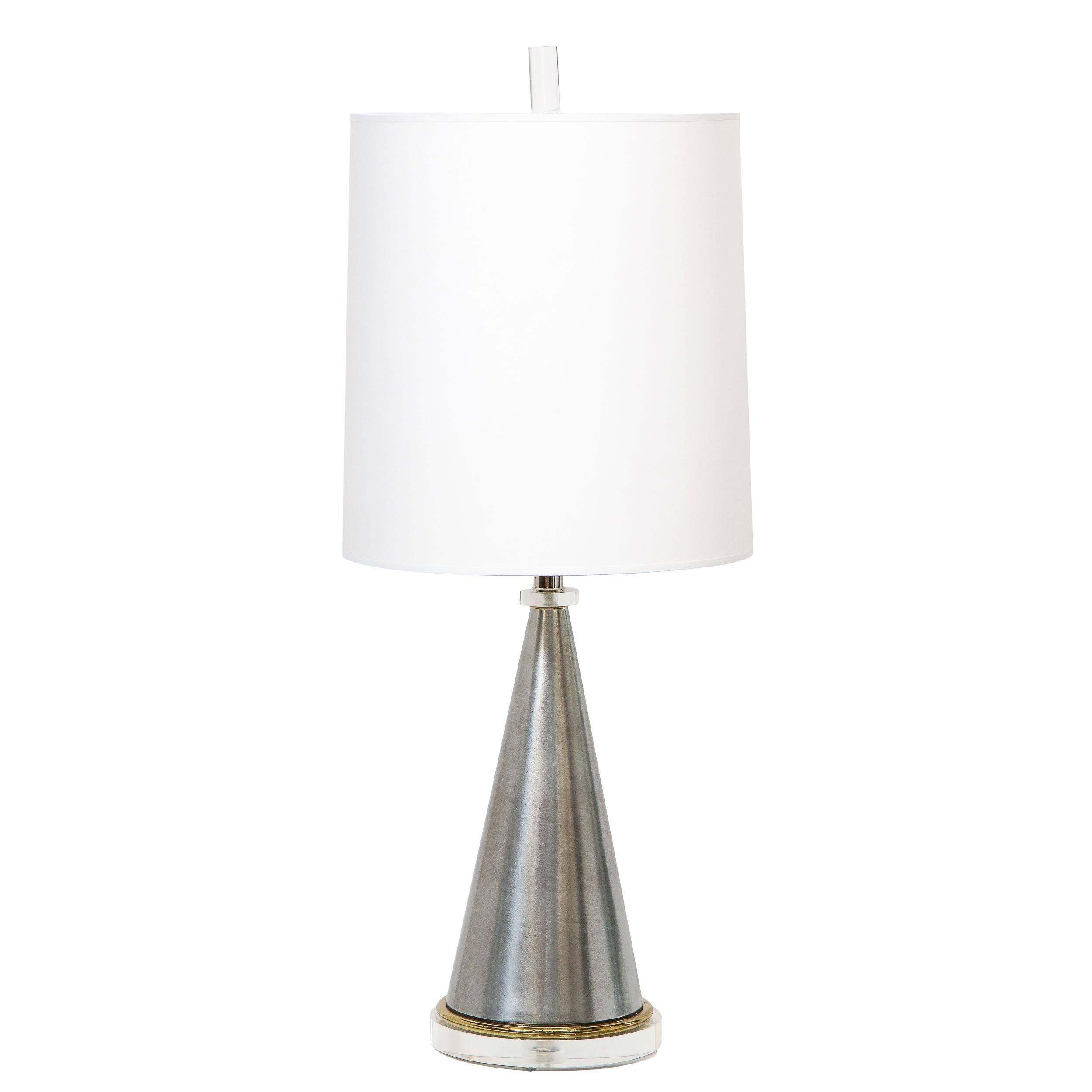 This stunning pair of table lamps were realized in the United States, circa 1960. They feature circular translucent Lucite bases with circular brass detailing supporting conical tapering brushed aluminum bodies. The lamps offer a ringed Lucite