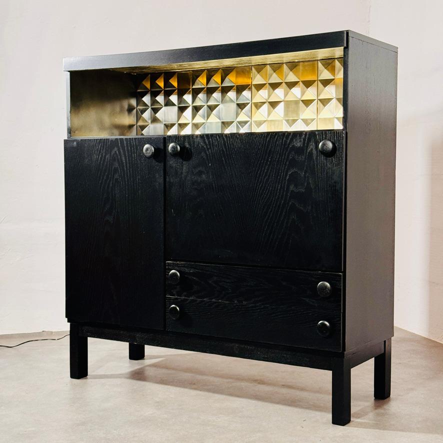 Mueble bar brutalista vintage de roble ebonizado.  
Precioso contraste entre el oscuro exterior y el colorido interior con ingeniosa iluminación fluorescente tras cristal acrílico. 
Esta iluminación puede encenderse y apagarse mediante un