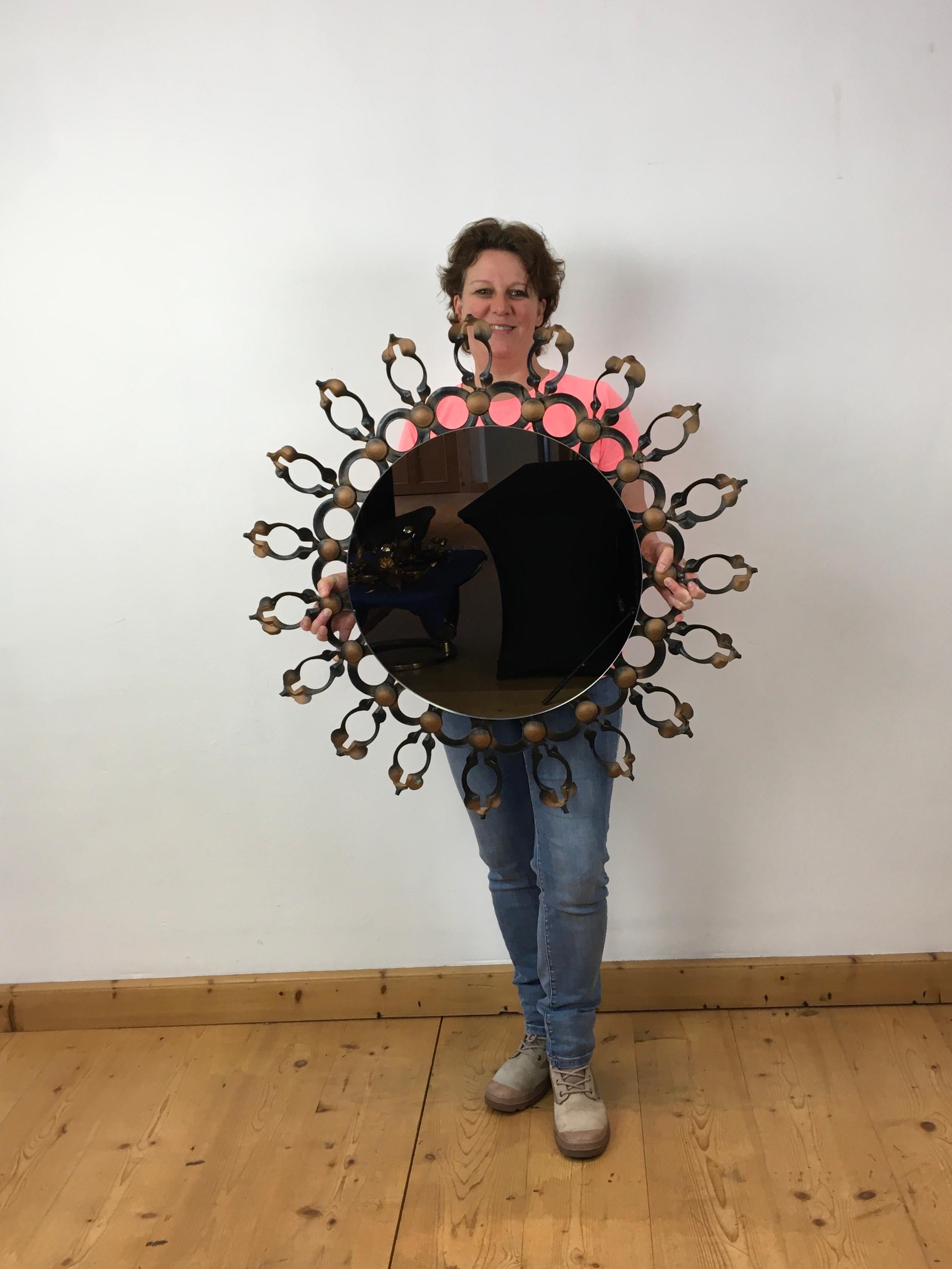 Large brutalist sunburst mirror - round wall mirror of the 1960s. 
A Mid-Century brutalist iron mirror. 
Hand-made / hand-crafted black - painted iron frame with golden - copper colored accents. 

This 1960s round wall mirror which will look