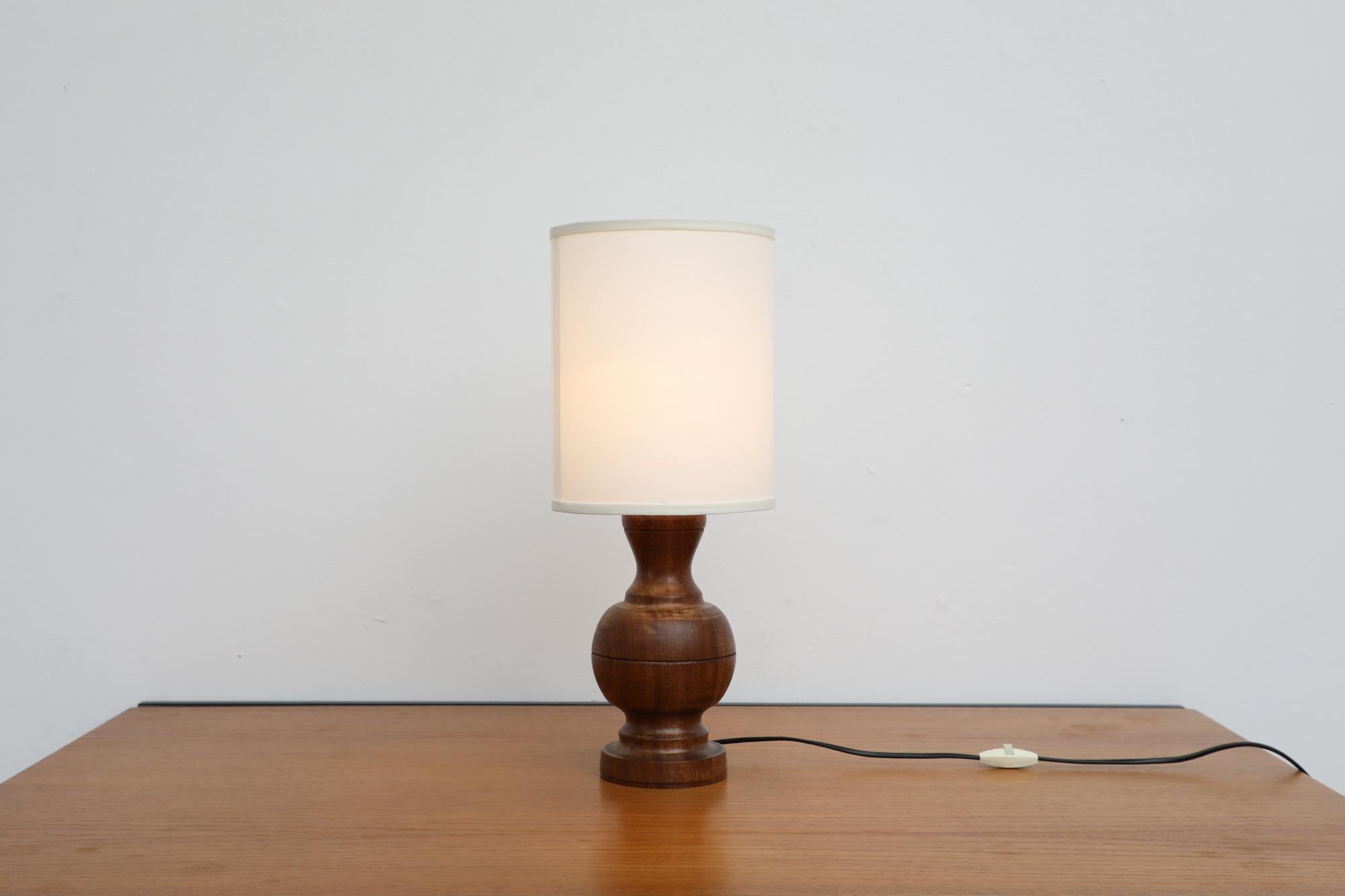 Mid-Century Brutalist table lamp with beautiful hand carved wood base. In the style of Uno Kristiansson. The lamp has a newer linen shade. In otherwise original condition with visible wear consistent with its age and use.