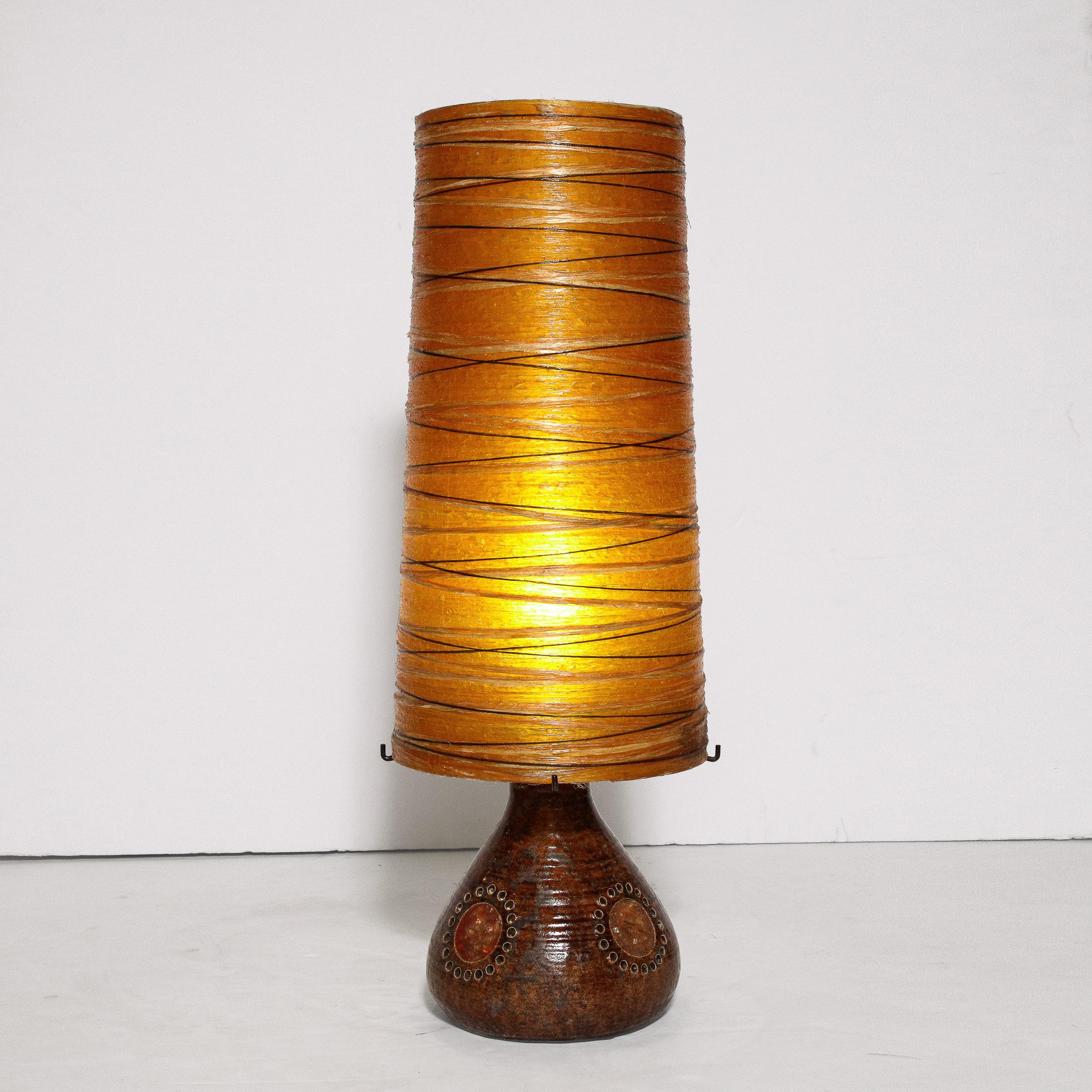 This beautiful Mid-Century Modern brutalist table lamp was realized in France, circa 1960. It features a spherical body in a rich umber hue with spherical detailing in brick red encircled by pierced circular incisions- a la Georges Pelletier. The