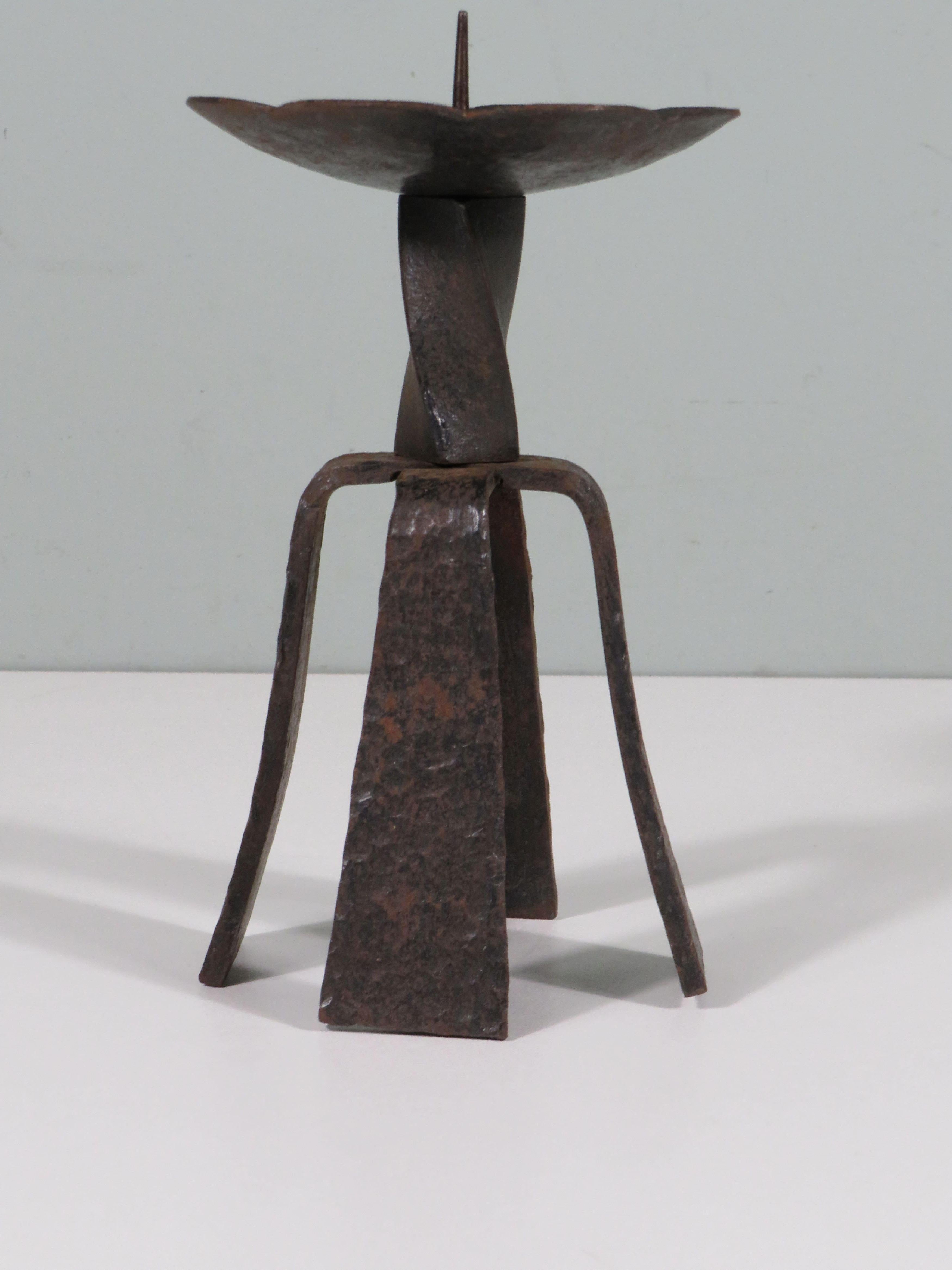 Hand-forged, twisted and hammered candlestick.
The candlestick has 4 different, forged and hammered legs that are attached under a twisted center piece. Above this, the scalloped drip tray is attached with a pin.
The candlestick has a black/brown