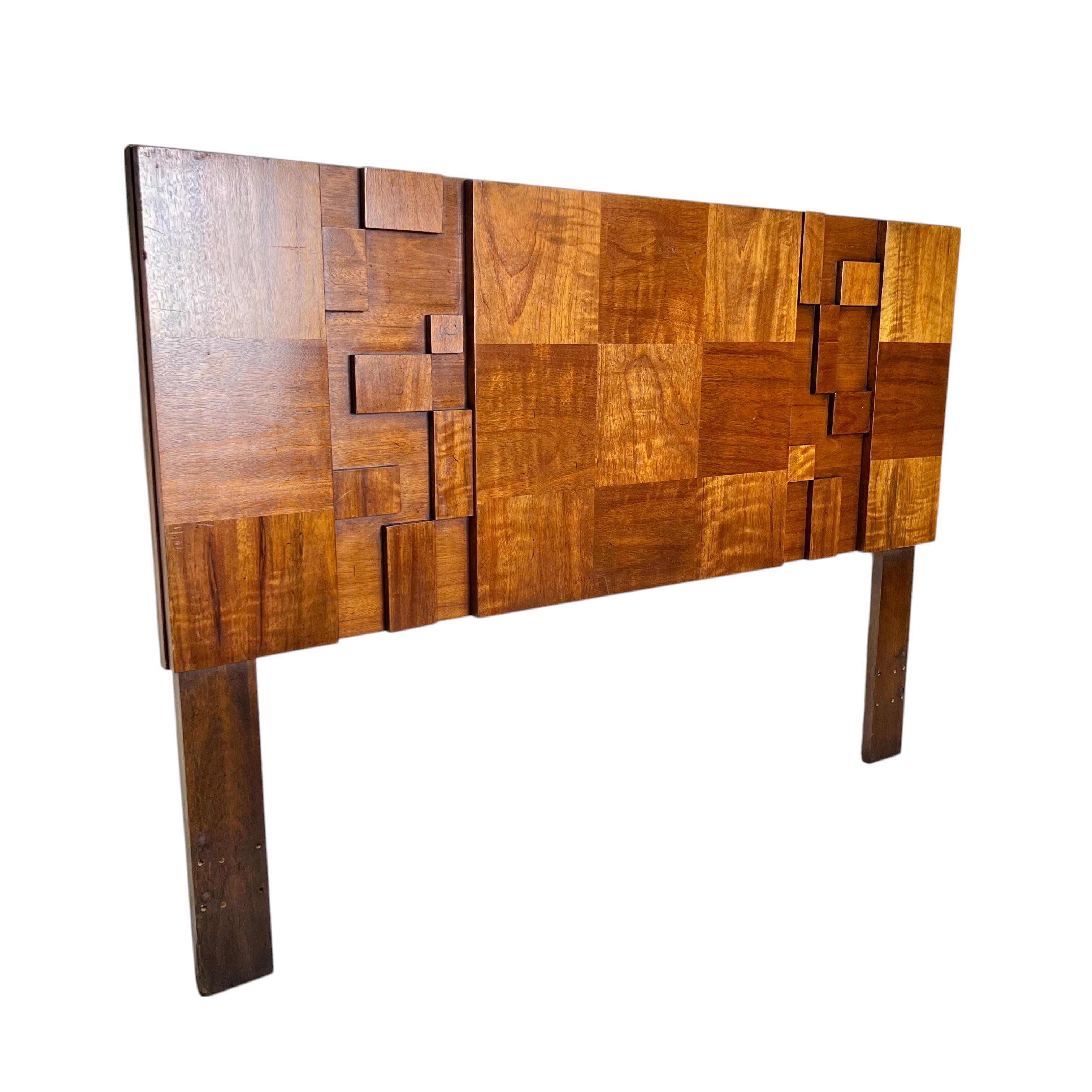 A Mid 20th century brutalist walnut queen or full headboard by Lane for the Staccato collection. The Paul Evans style design features overlayed checkerboard tonal walnut panels accented with dimensional rectangular appliqués. The legs have been