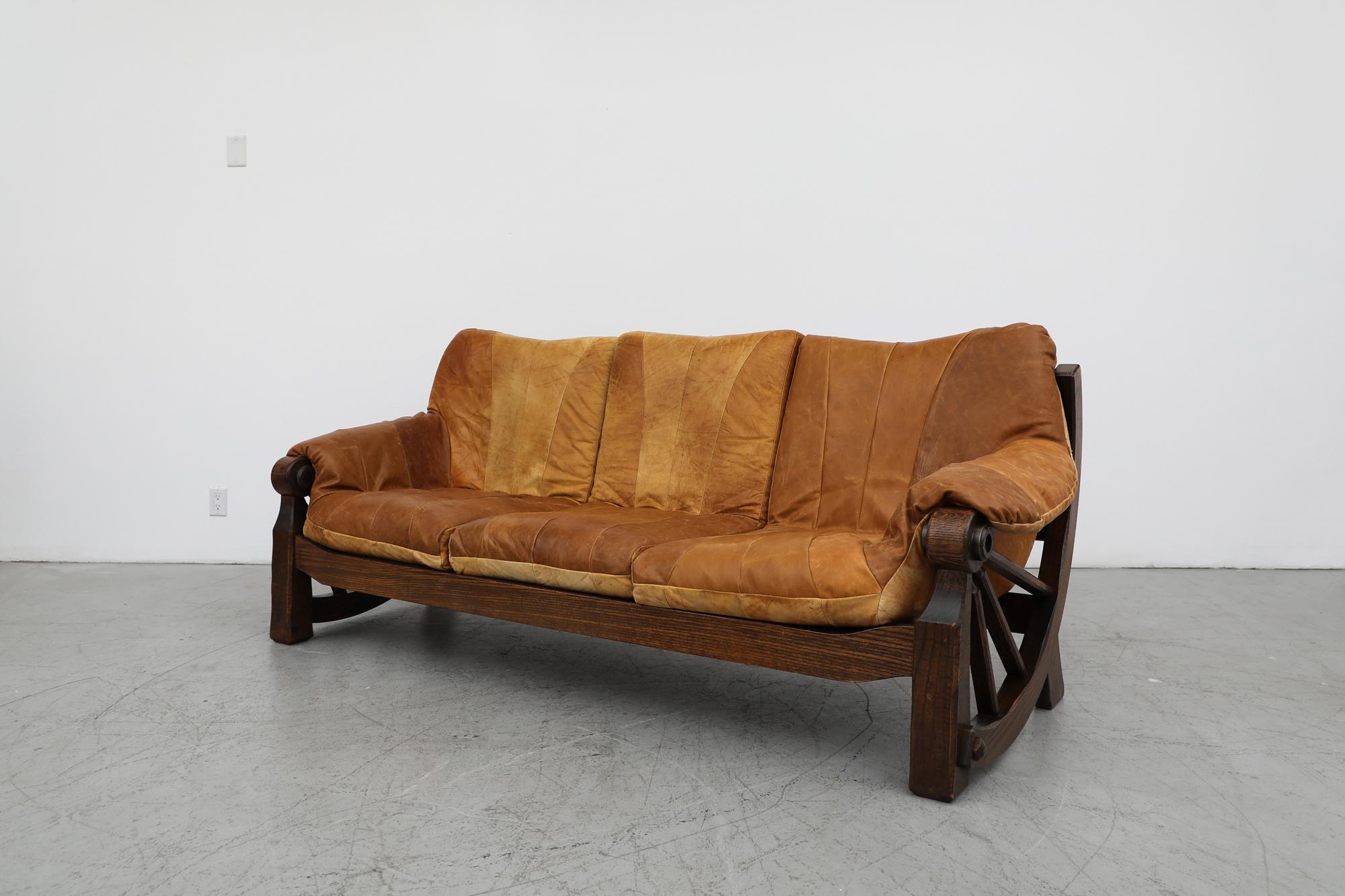 Mid-Century Brutalist leather patchwork sofa with western style carved oak frame inspired by the wagon wheel. Lightly refinished frame, in otherwise original condition with visible remaining wear and patina that is consistent with its age and use.