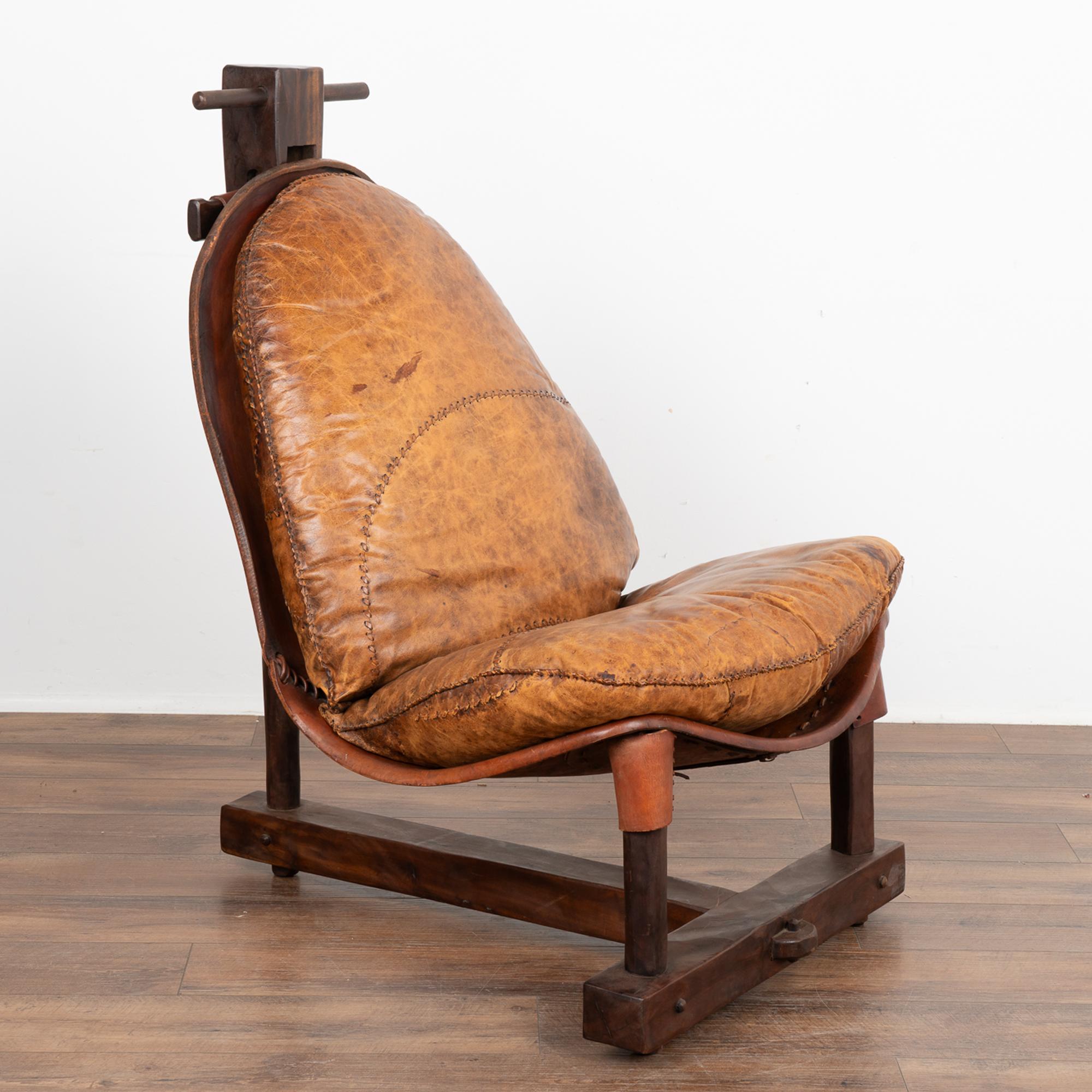 Mid-Century brutalist armchair in stitched vintage leather, designed in Brazil in the 1960's.
The patchwork leather cushion on top with decorative stitching is reminiscent of an old baseball glove and rests in a strong wood frame.
The vintage
