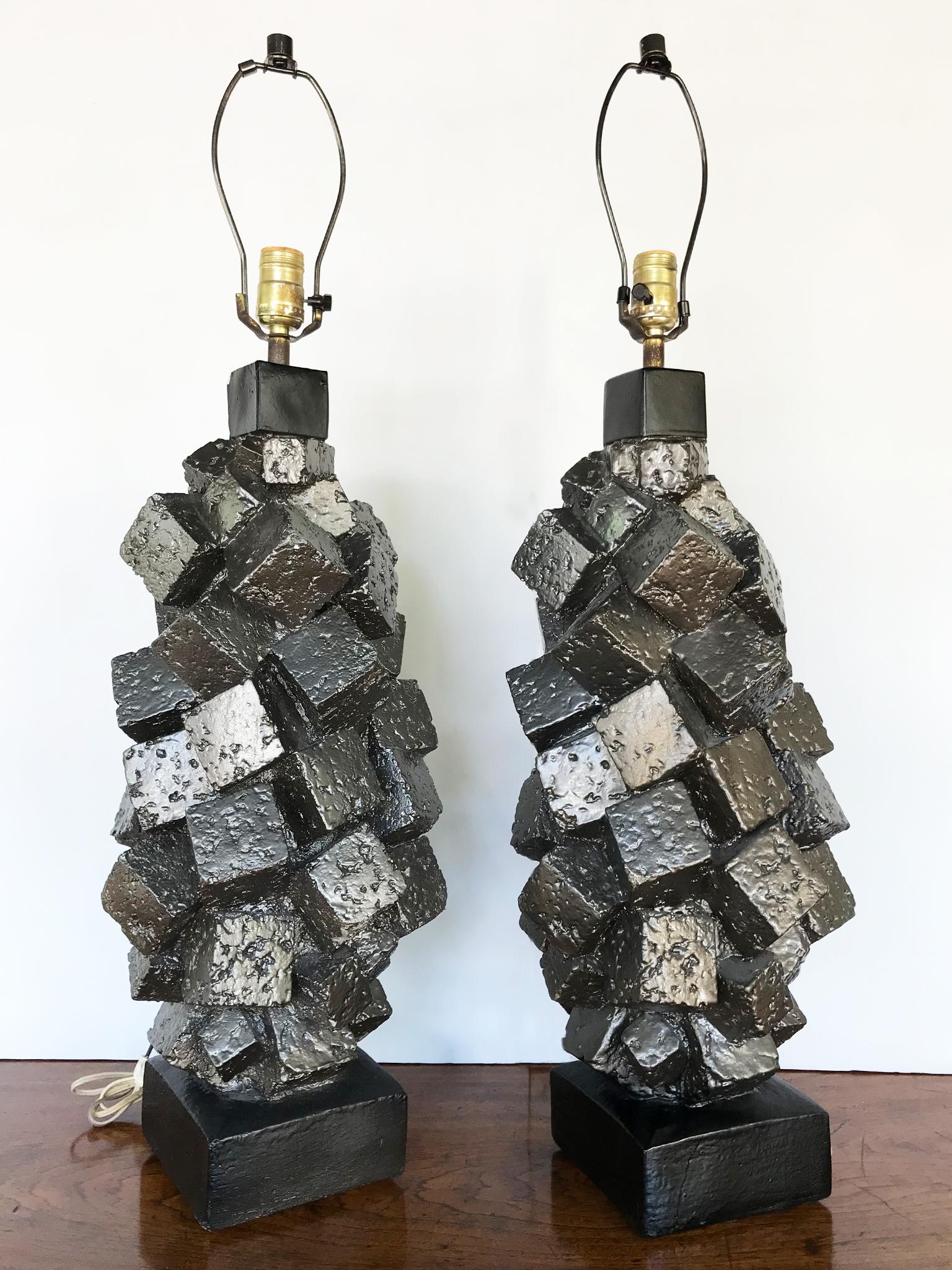 A curious pair of brutalist table lamps comprising of glazed cast plaster. Mid-20th century these lamps are remarkable for their unusual cube forms, which are made to appear as clusters of magnetized metal. The silver metallic glaze adds to this
