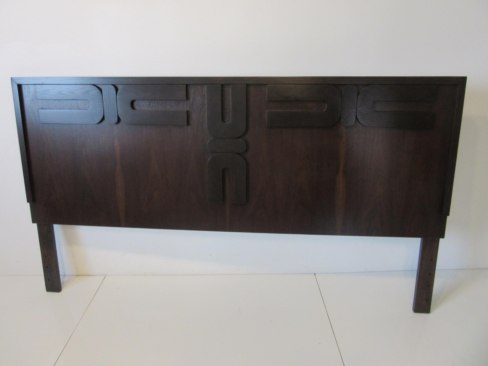 A ebony toned queen sized headboard with walnut backing having a dark and lighter affect to show off the wood grain. A Brutalist styled design application applied to the front gives this piece a subtle textured feeling of interest, manufactured in