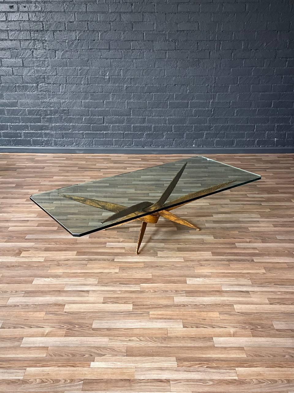 Condition: Original Vintage Condition 
Materials: Torch Cut Steel, Original Glass Top

This striking Mid-Century Modern coffee table from the 1970s features a sculptural base crafted from torch-cut steel with a rich, hand-applied gold patina. The