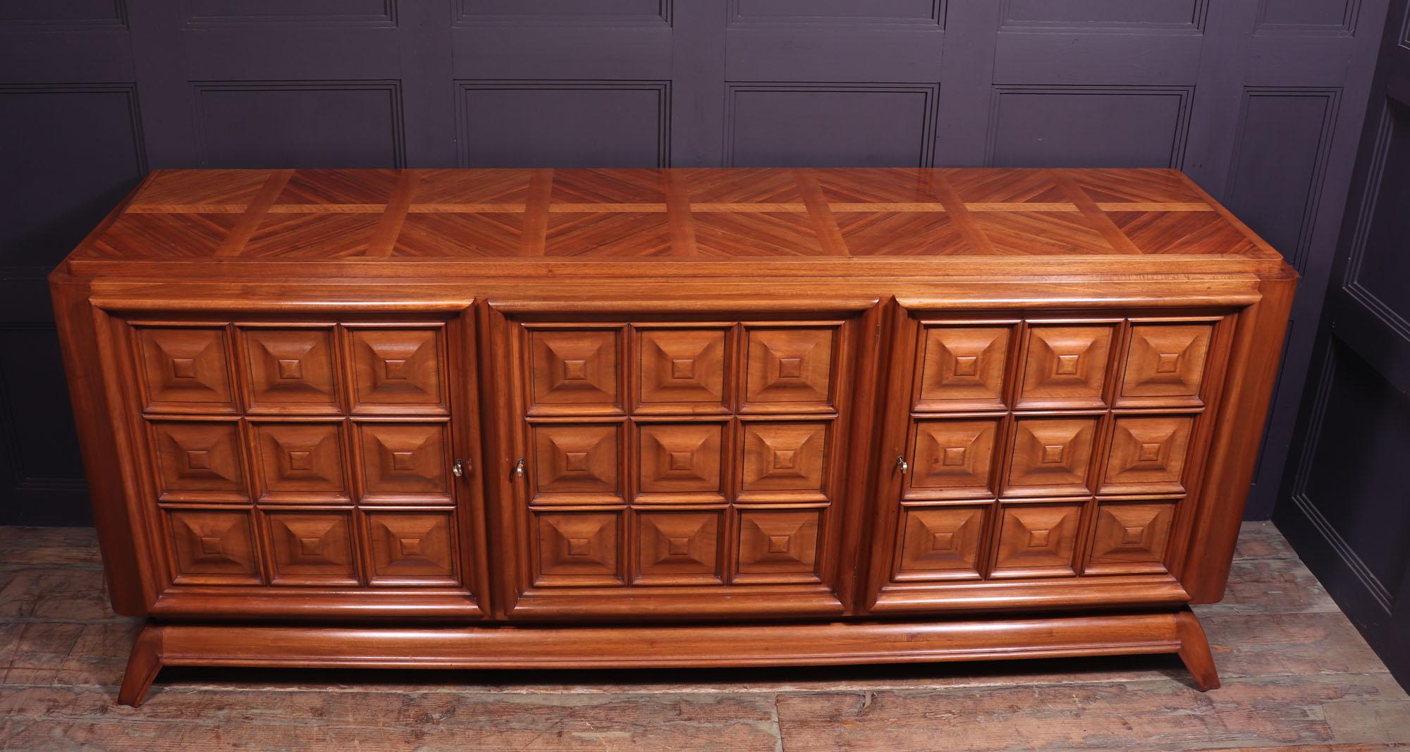 Mid-century Brutalist sideboard 
This Brutalist extra large sideboard was produced in France in the 1940’s in walnut, it has three doors with solid panel doors with symmetrical paneling, behind is a large storage are with adjustable shelving and
