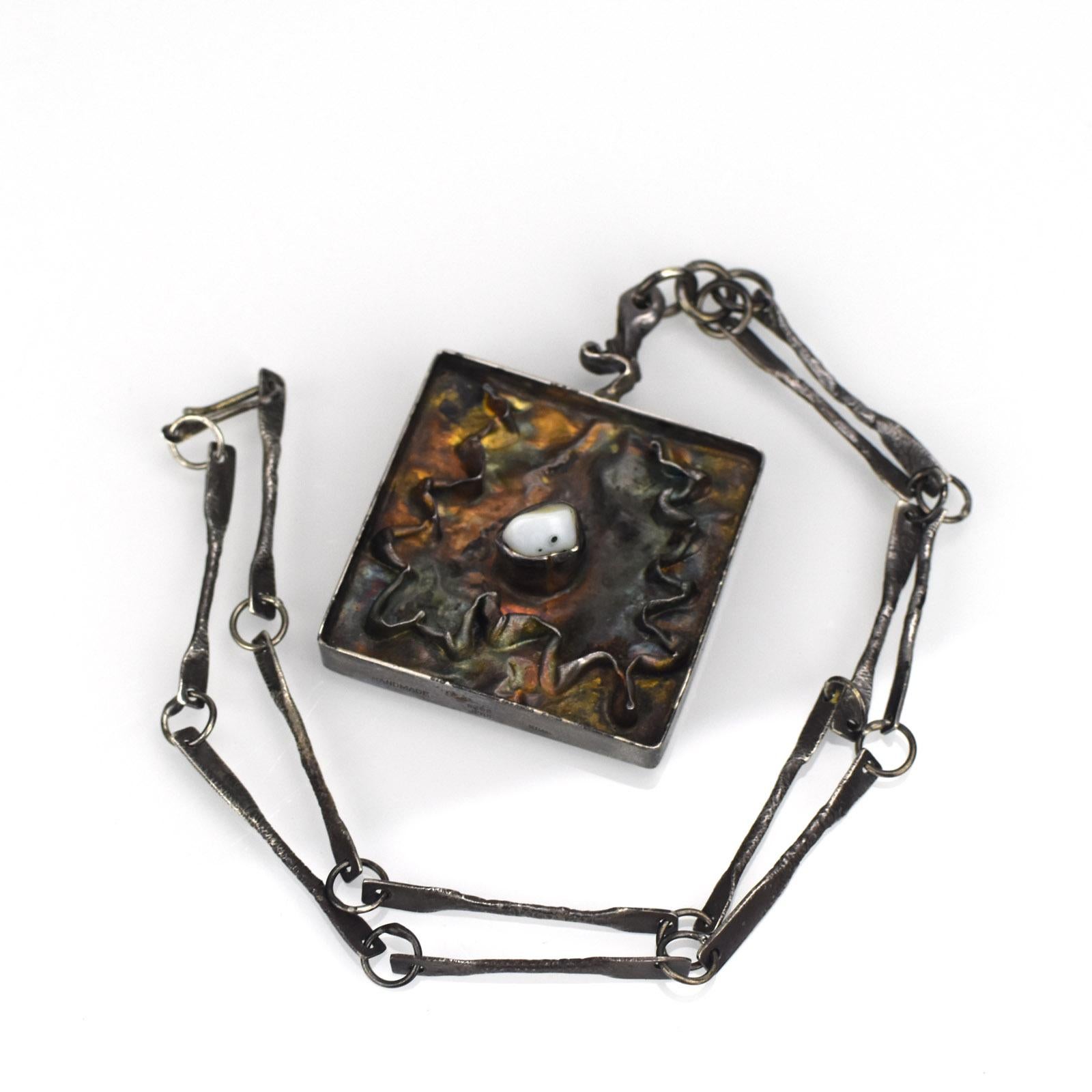 This captivating mid-century modern necklace exemplifies the artistry of Jens Peter Clausen Gudjonsson, a renowned Icelandic designer known for his distinctive brutalist style. 

Crafted from sterling silver, the substantial pendant features