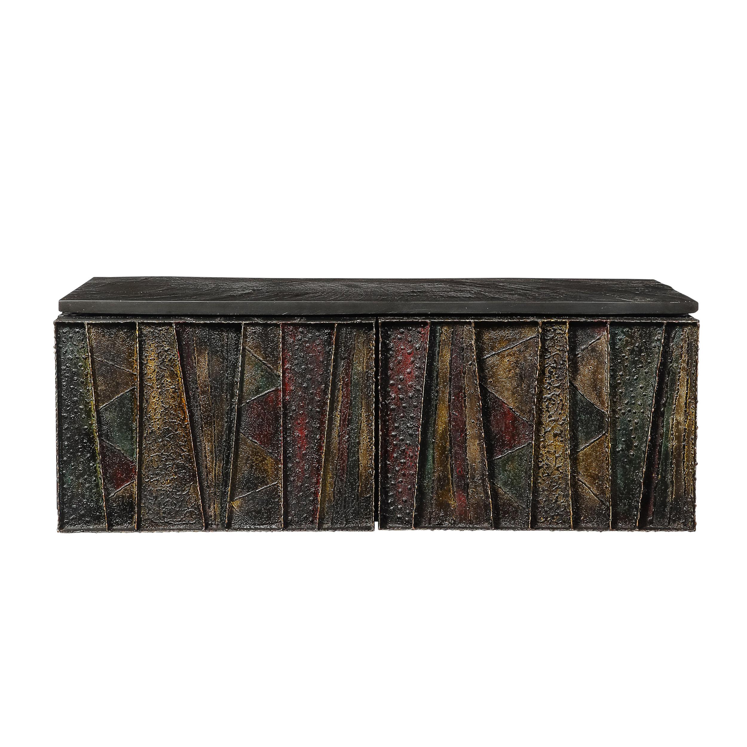 An iconic design by legendary American studio craftsman Paul Evans, this mid-century Brutalist wall-mounted cabinet exemplifies his innovative artistry and bold industrial aesthetics.

This lovely cabinet features a geometric patchwork of