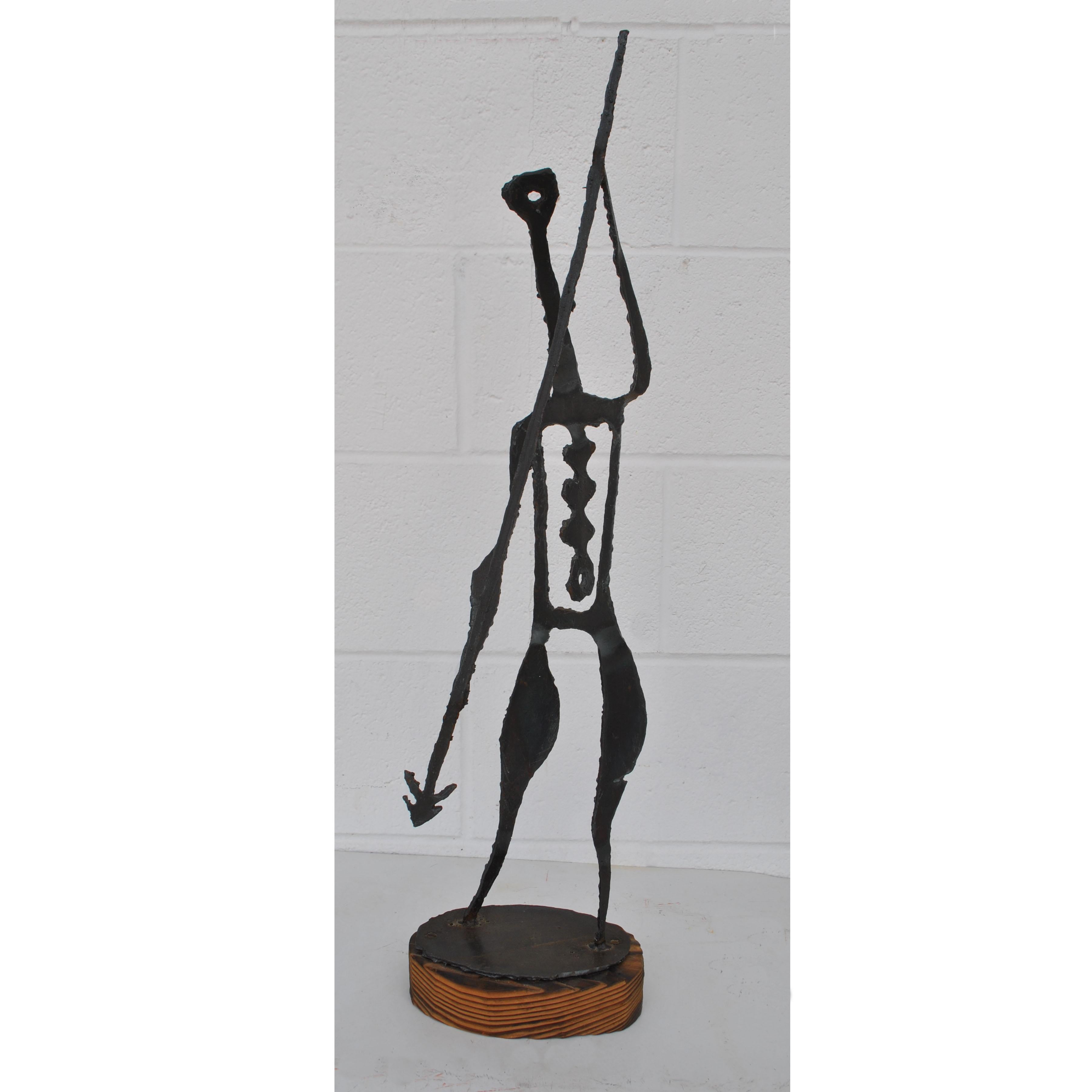 Mid-Century Modernist Brutalist metal sculpture depicting a spear carrying warrior. The scorched torch cut molten metal is mounted on a wood block. Measures: 31