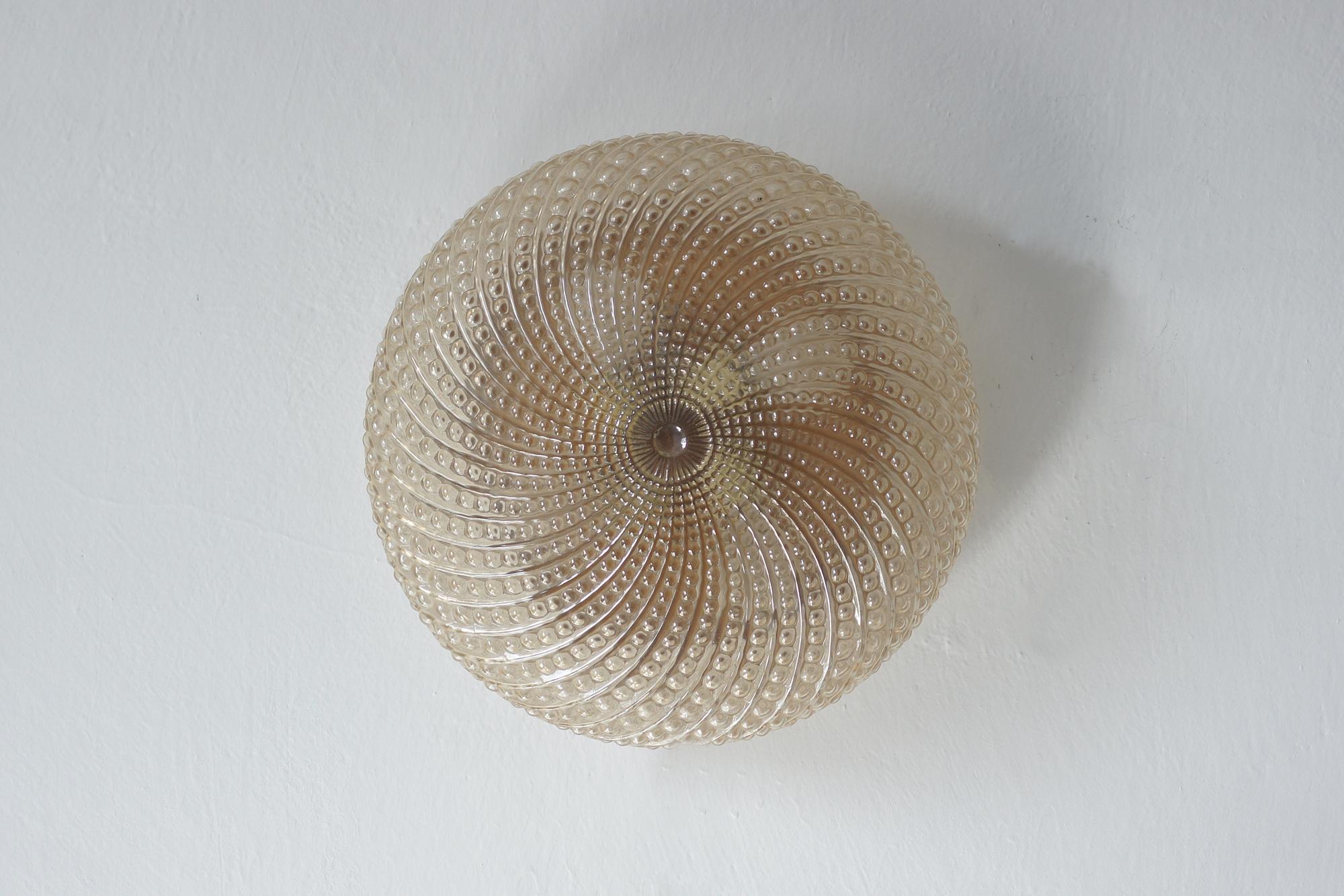 Esta lámpara de techo decorativa es un ejemplo de la artesanía europea del diseño de iluminación de la segunda mitad del siglo XX. Es de cristal ámbar con una textura única, hecha a mano.

Vidrio macizo teñido en un cálido tono ámbar. Su superficie