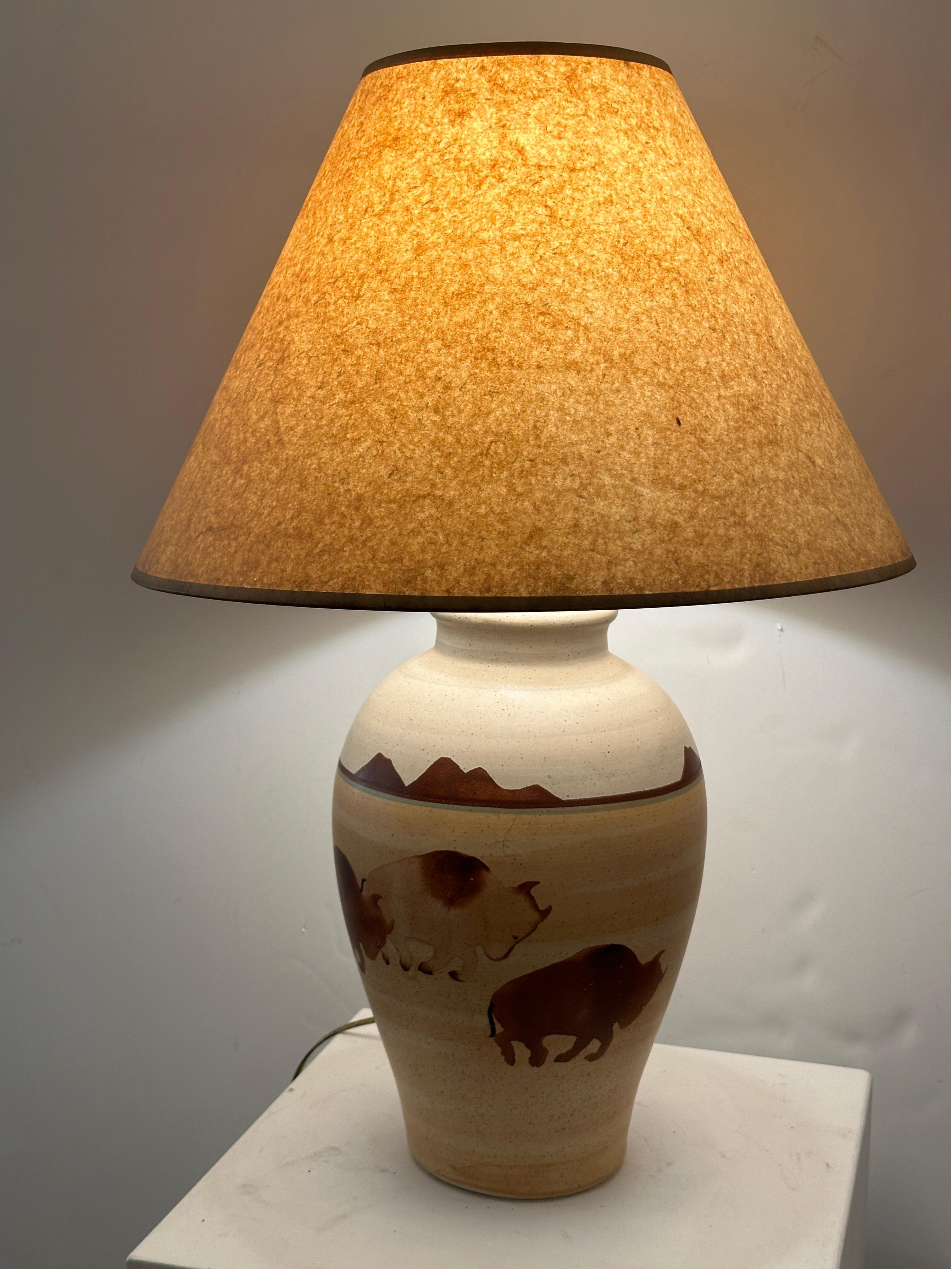 This vintage ceramic lamp by California Ceramic Designers Inc. features a Southwestern landscape around the circumference with three nicely detailed stampeding bison centered in the front. The scenery is reminiscent of the familiar representations