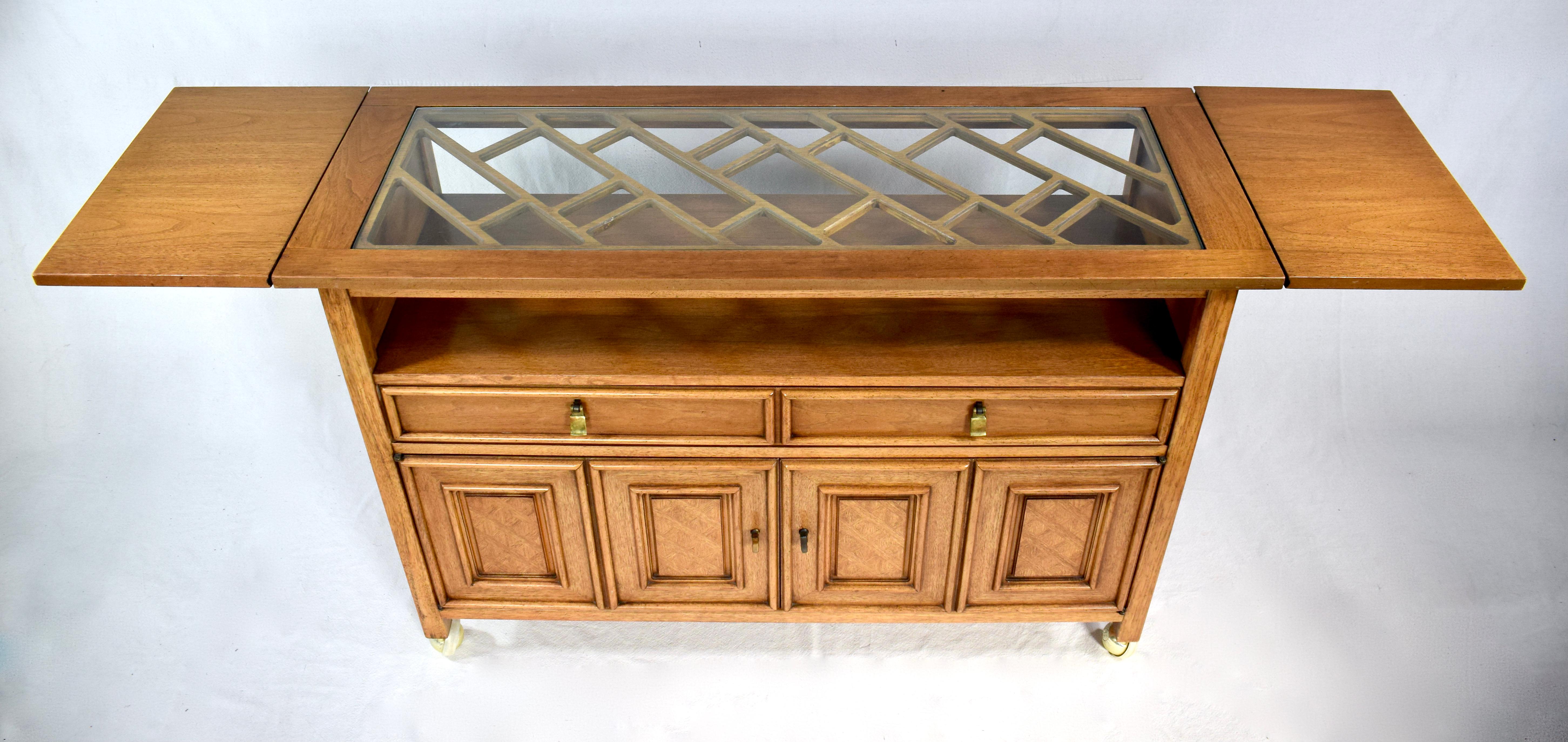 A multifunctional two tiered bistro style buffet or serving table with two dovetailed felt lined drawers, full body second tier and spacious cabinetry beneath. Beautifully Finished on all sides boasting removable glass & faux bamboo trellis insert
