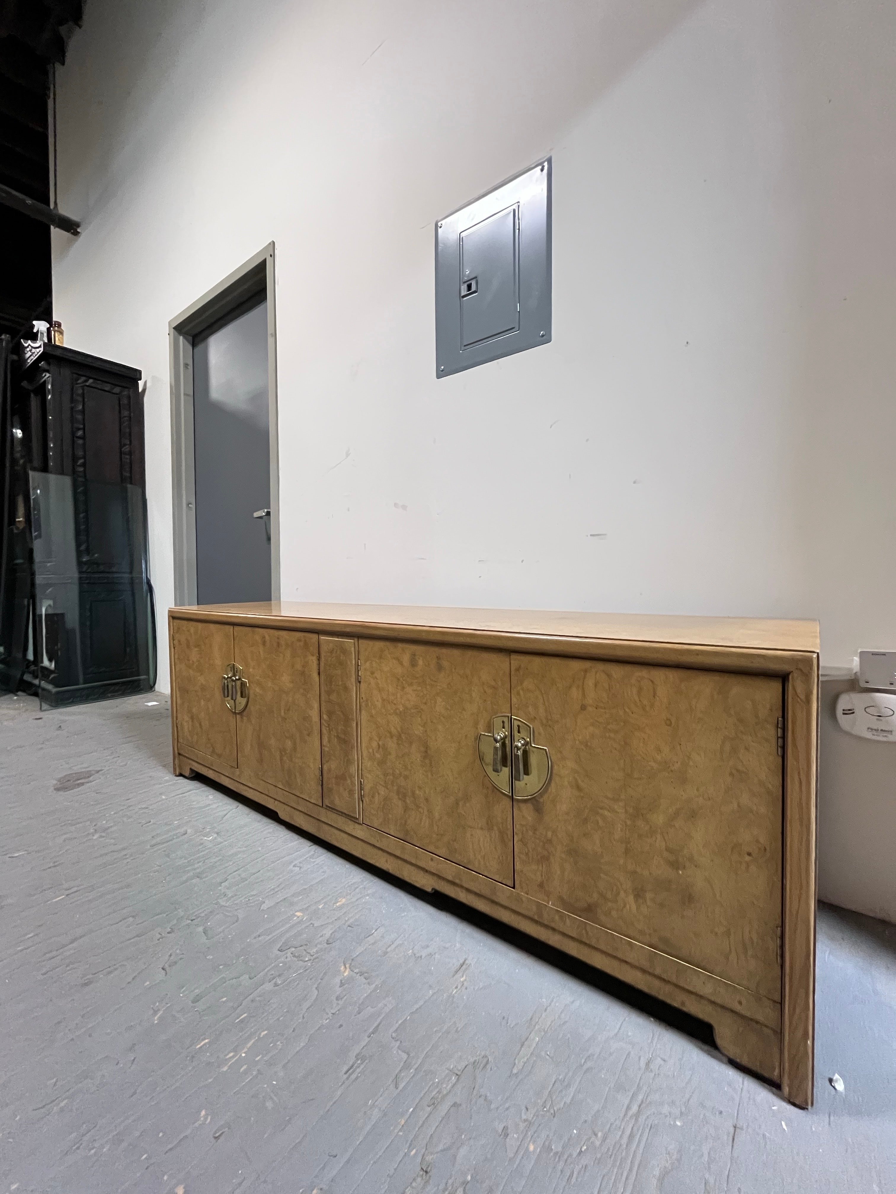 Beautiful long and low Burl credenza in the styling of Michael Taylor for Baker's Far East Collection. Wonderful burl offset by solid brass hardware. This piece has ample storage with four swinging cabinet doors and 2 large storage areas. Simple and