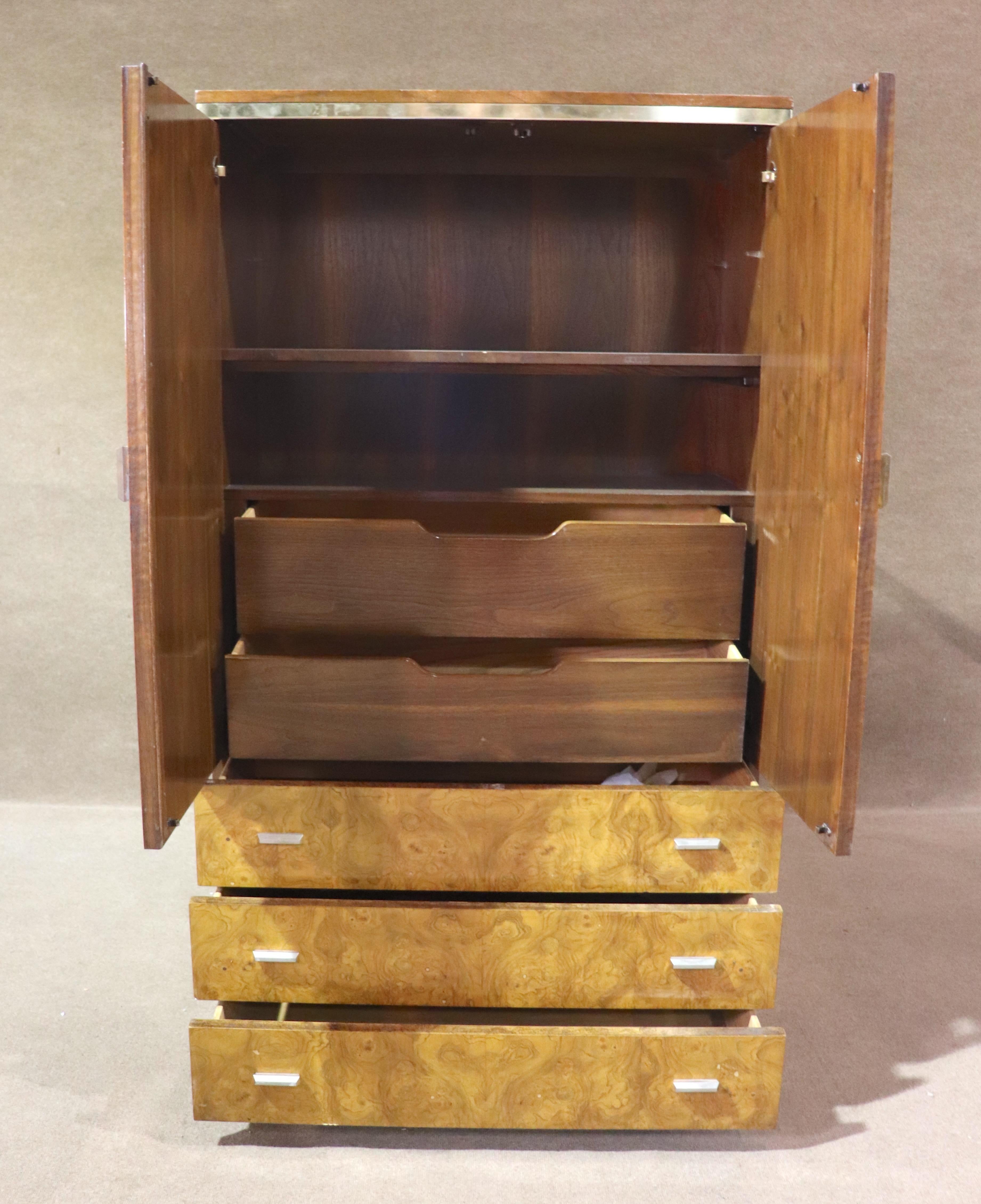 Armadio alto in stile mid-century modern di Mt Airy in radica di noce e ottone. Due lunghe ante nascondono un piccolo armadio guardaroba con ripiano estraibile e due cassetti. La metà inferiore presenta tre ampi cassetti.
Si prega di confermare la