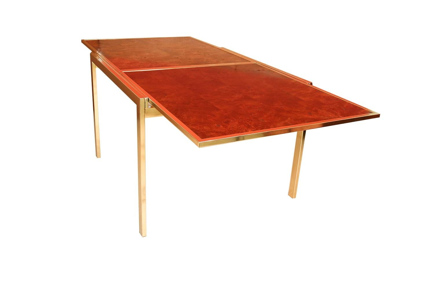 Exceptional Mid-Century Modern burled olive ash and brass extension draw dining table in the style of Milo Baughman. This striking vintage burled wood draw dining table in original good condition with fine brass metal work and details throughout. An