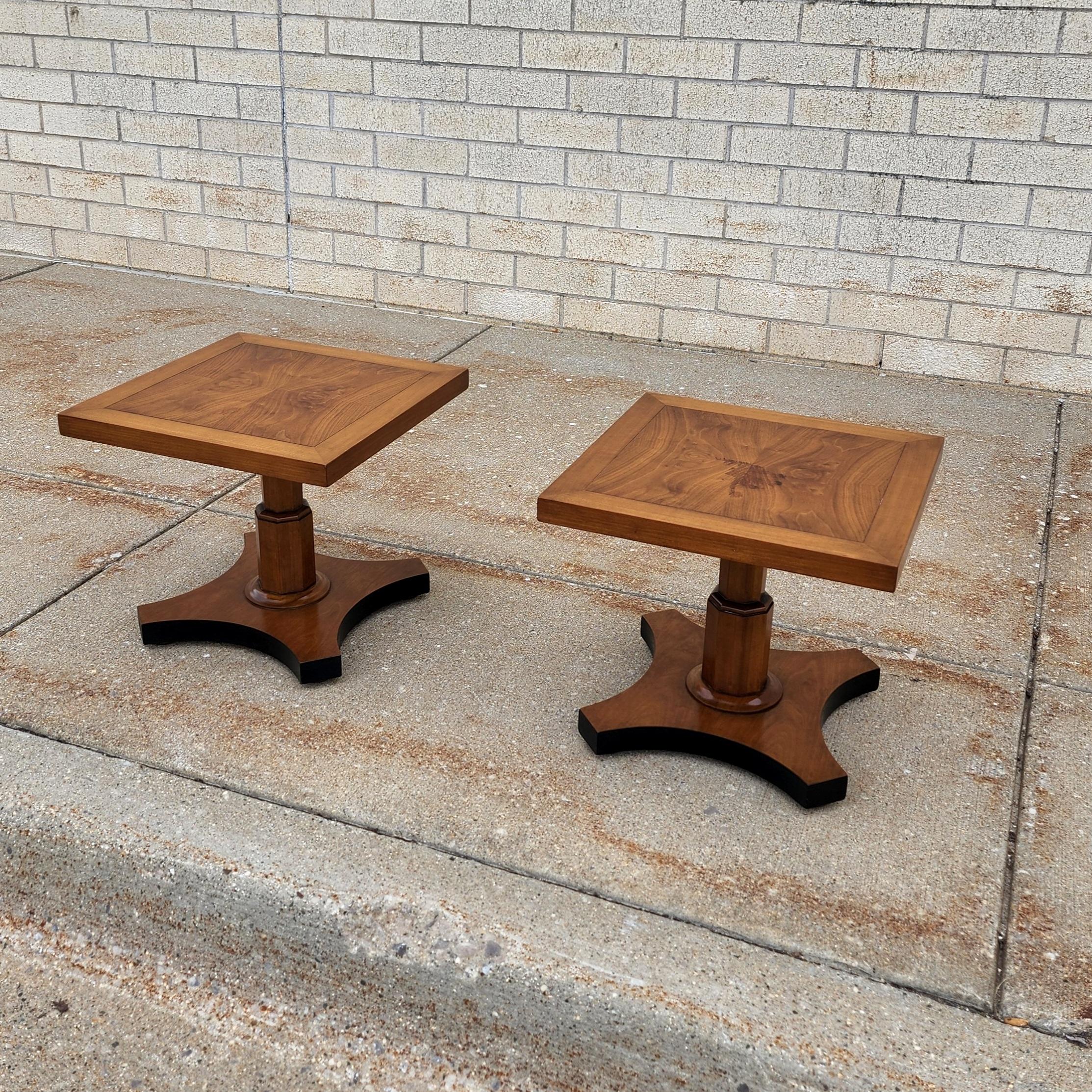 This beautiful pair of end tables have a stunning burl wood walnut top resting on pedestals with an inverted quatrefoil walnut base. The sides of base are accented in a satin black lacquer finish. They are crafted in high quality by Baker Furniture.