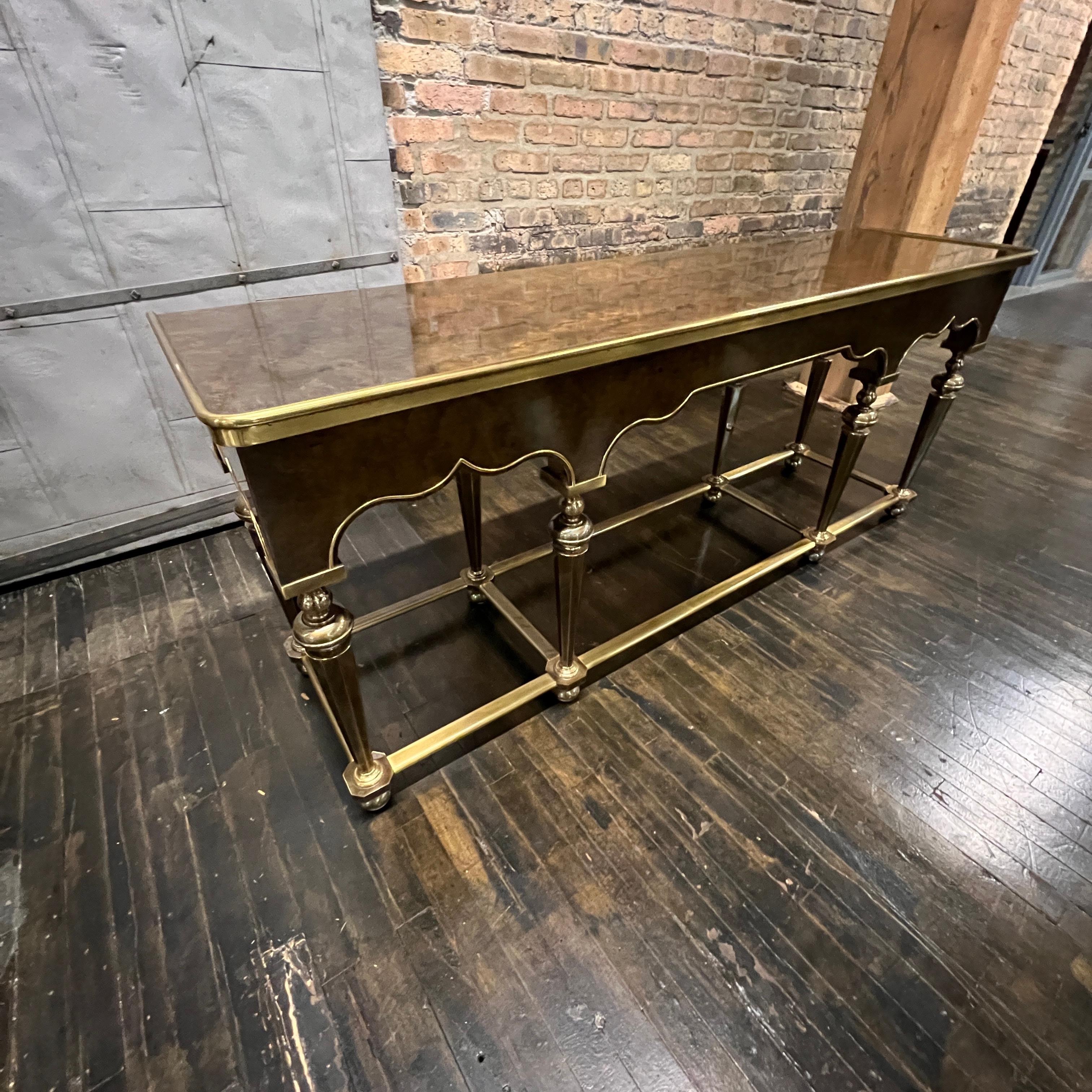 Lovely Hollywood Regency style brass and burl wood console attributed to Mastercraft.  It has a burl wood top and apron that have a lovely brass detail around all the arched edges.  It sits on eight brass legs with brass supports between the legs. 