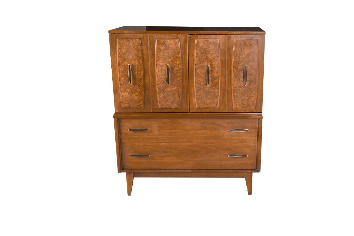 A classic Mid Century Modern walnut tallboy dresser with burled walnut center doors by a division of Broyhill, “Lenoir Furniture Company”. A handsome example of American craftsmanship. Stunning walnut highboy dresser with sculptural accents svelte