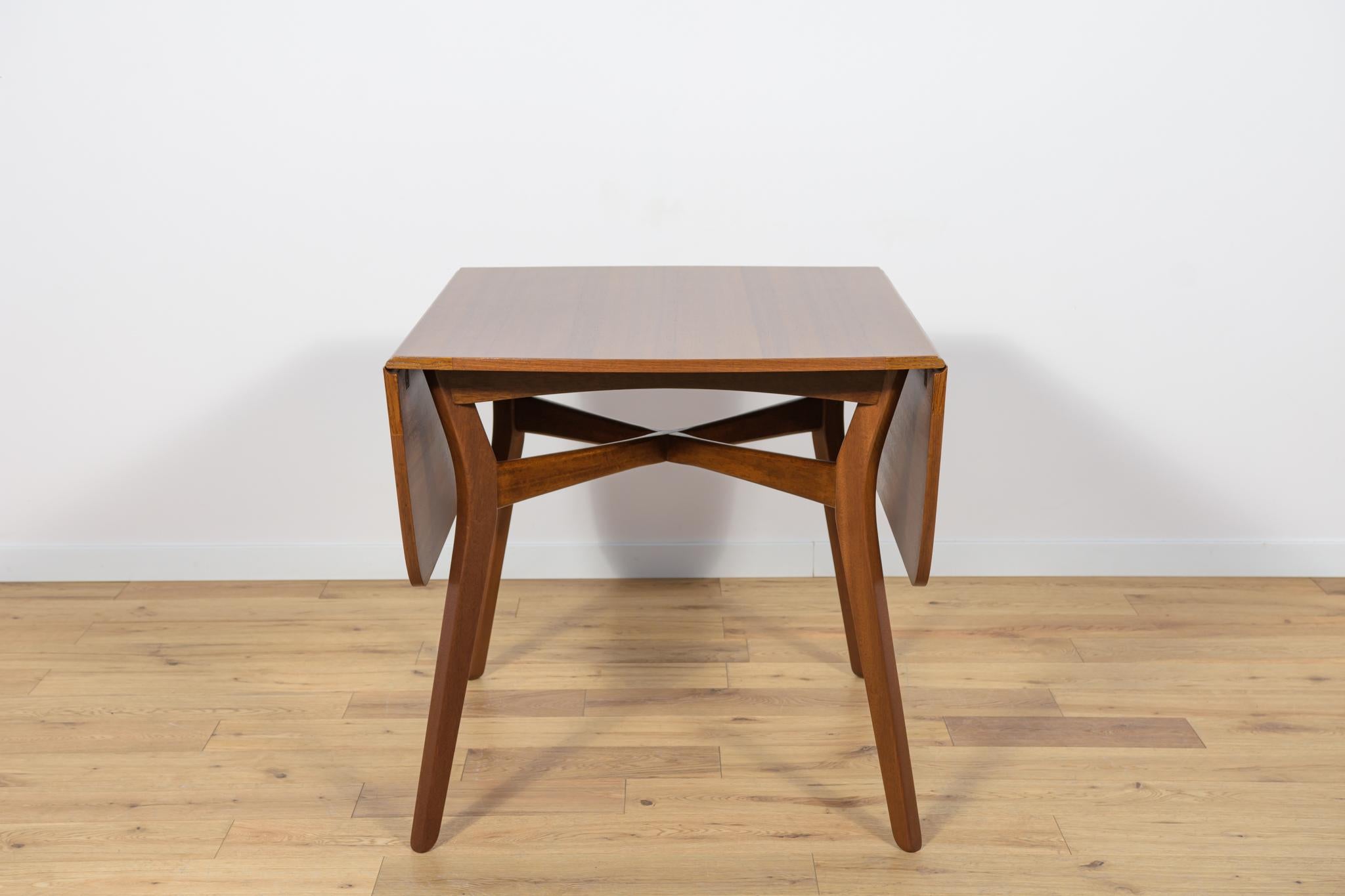 This British extendable dining table in teak was produced in the 1950s by G-Plan. Its wood elements have been cleaned from the old surface and painted in oak-coloured mordant and polished with strong semi lette lacquer. The table is adjustable from