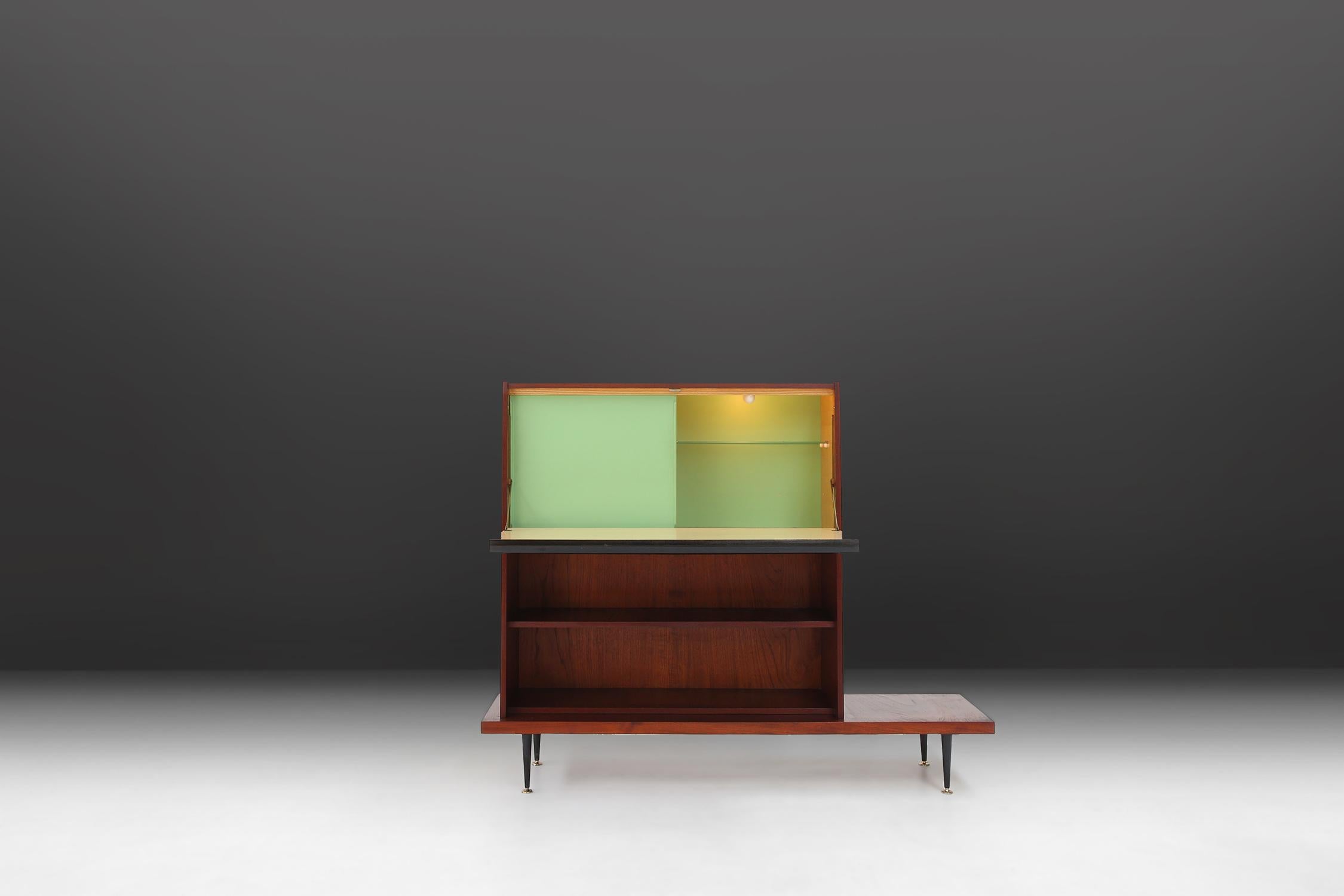 unique midcentury cabinet made in the 1960s of teak wood with some black details in the handle.
If you open the cabinet you find a great refreshing green color for with a light inside.