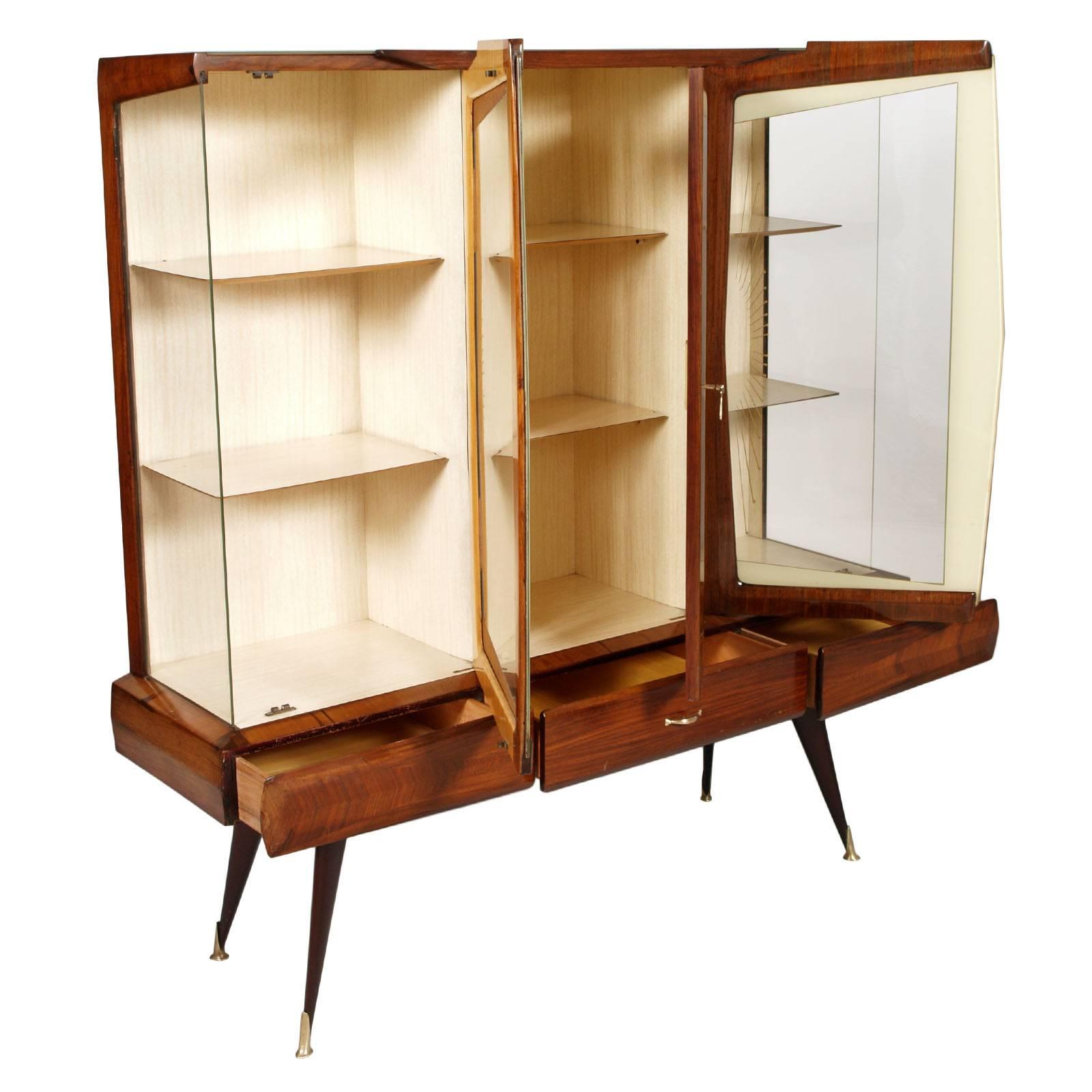 Mid Century , in walnut, rosewood and maple bar cabinet attributed to Vittorio Dassi designer. All the external parts are with curved edges, three drawers with golden brass handle, four legs with golden brass feet and a glass on the top. The