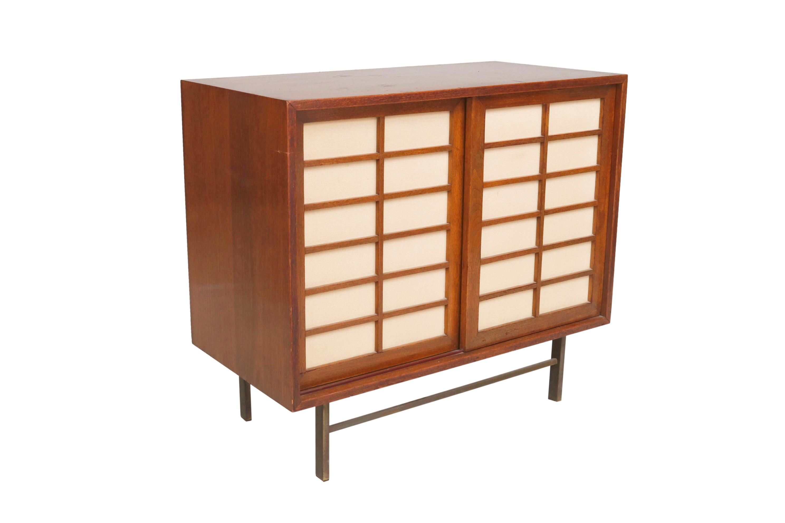 A compact midcentury cabinet. Brass stretcher base sliding doors interior shelves and drawers
Dimensions: 36