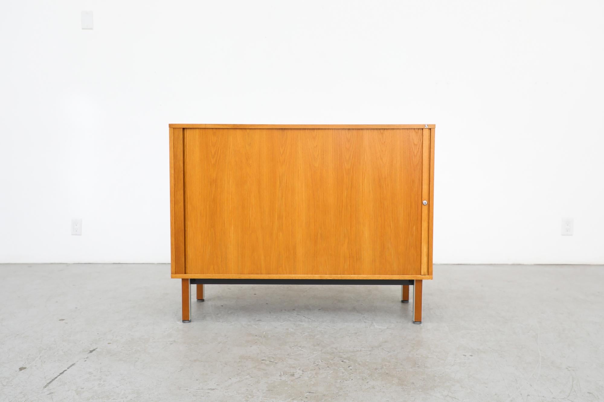 Mid-Century Nipu credenza or office cabinet with sliding locking tambour door, multiple cubbies and a stack of file shelves. The trays are molded plastic with ribbed treads inside. Perfect for an artist or an office. Visible sun fading line on the