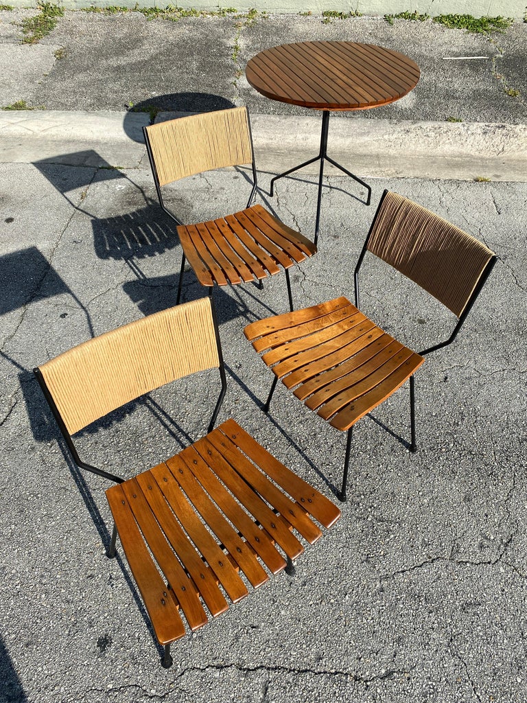 Stunning vintage cafe set designed by Arthur Umanoff for Raymor Furniture. Table features a wrought iron frame with wood slat surface. The 3 chairs have also a wrought iron frame with rope on the back rest and wood slats seats. Circa 1950s.

The
