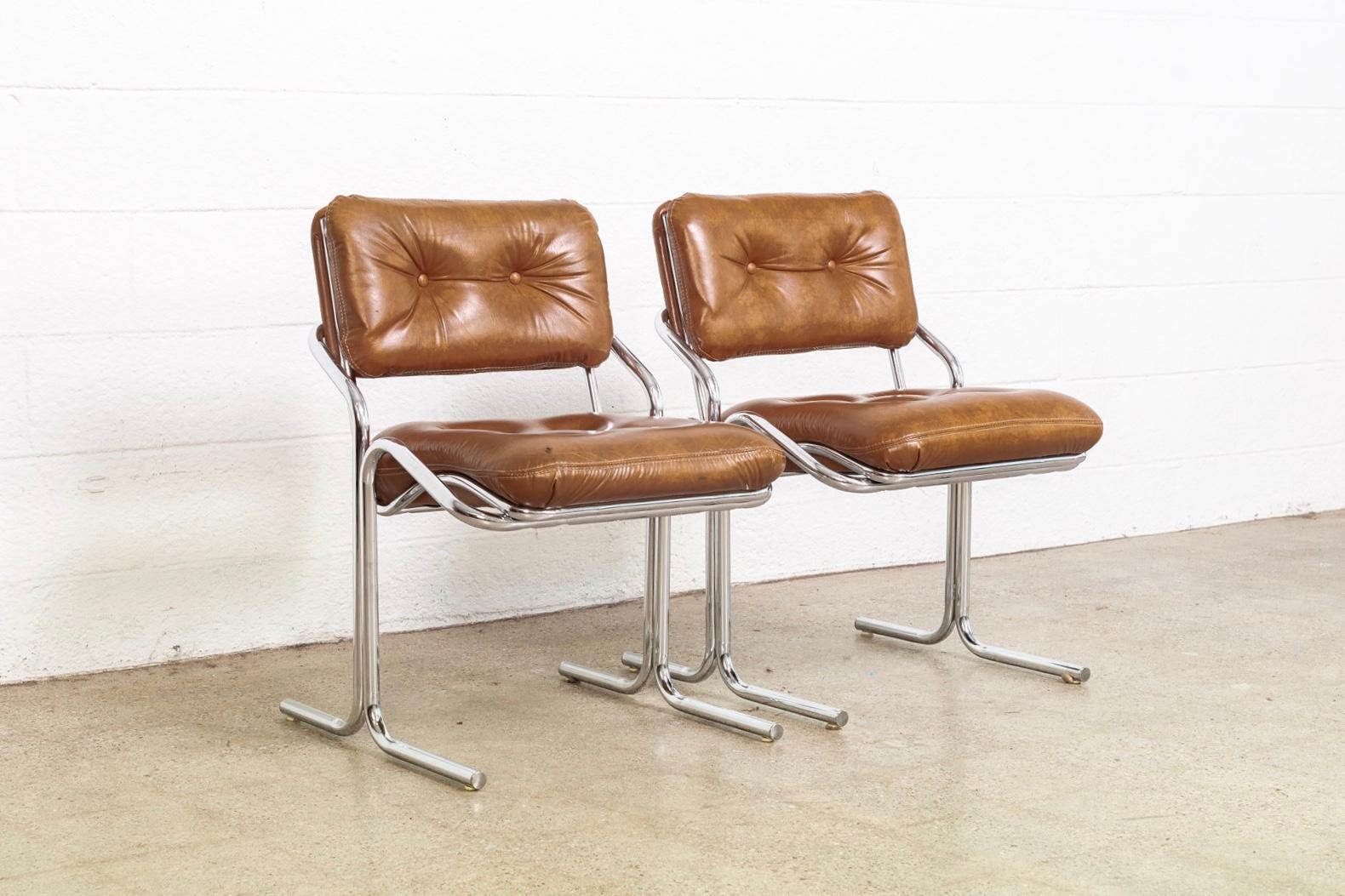 This pair of vintage midcentury side chairs was produced by Cal-Style Furniture Co. in 1981. They have fabulous 1970s style featuring a tubular chrome cantilever base with beautiful curvilinear form and cognac brown tufted upholstered Naugahyde