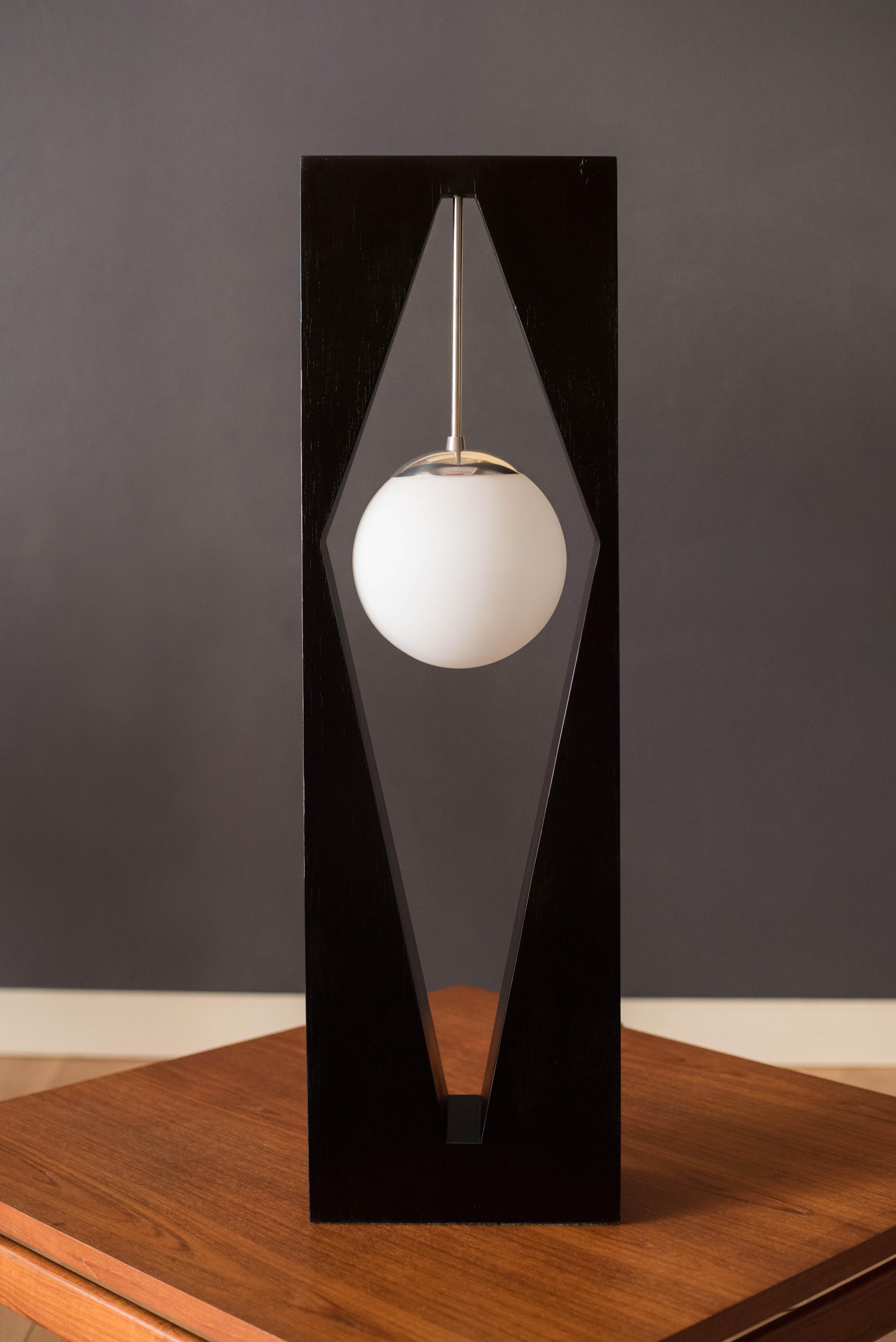 Mid-Century Modern accent table lamp manufactured by Modeline of California, circa 1970's. This unique piece will light up any space featuring a suspended frosted glass globe accented in chrome hardware and supported by a geometric black lacquered
